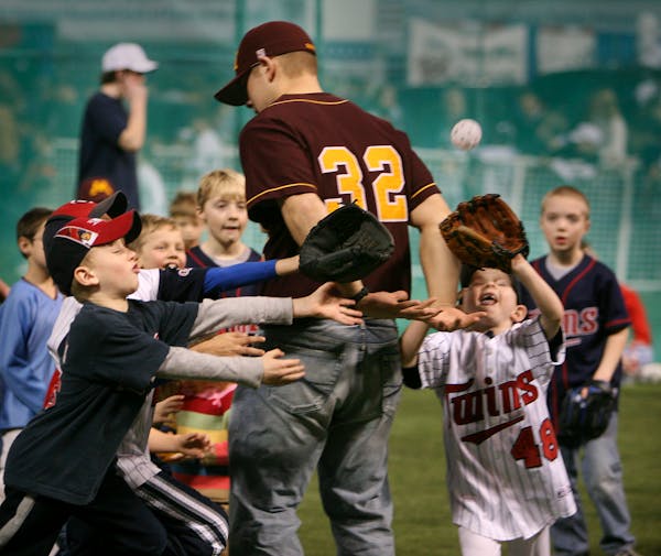 University of Minnesota baseball player Chauncy Handran, a junior, is swarmed by young Twins wannabees running down a whiffle ball during Twinsfest at