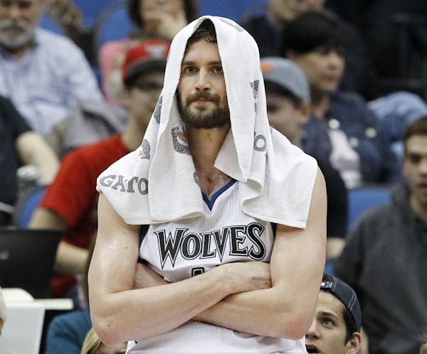 Minnesota Timberwolves forward Kevin Love sits on the advertisement stand during a timeout in the fourth quarter of the Timberwolves' NBA basketball g