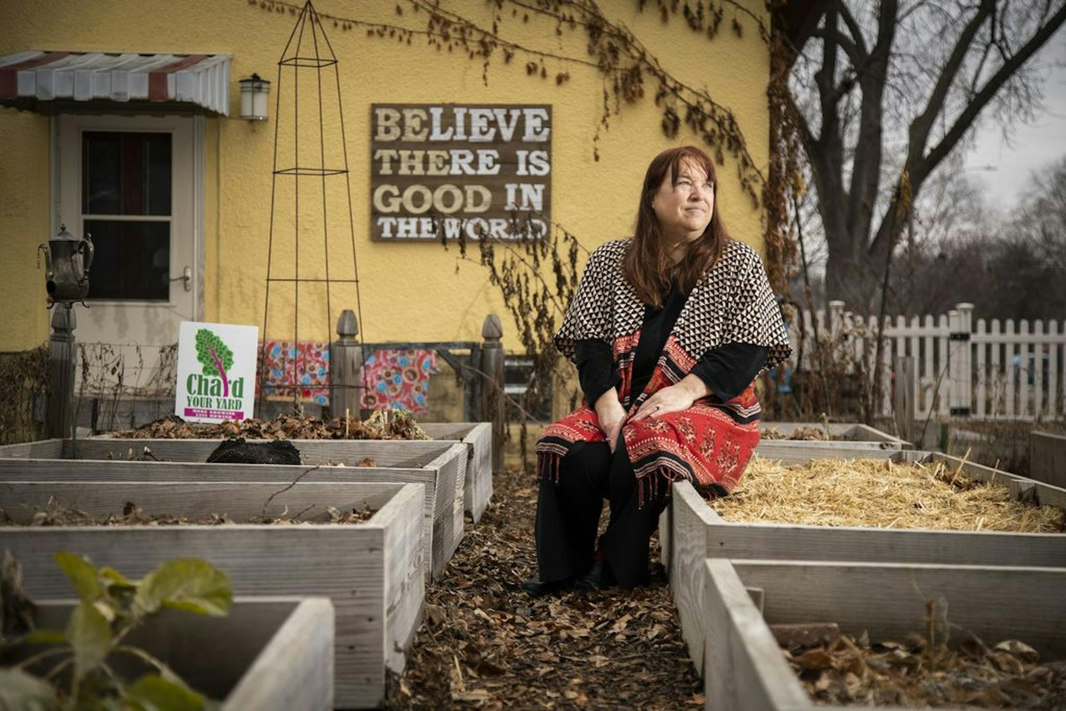 Leslie MacKenzie poses for a photo in her backyard with her raised garden beds.