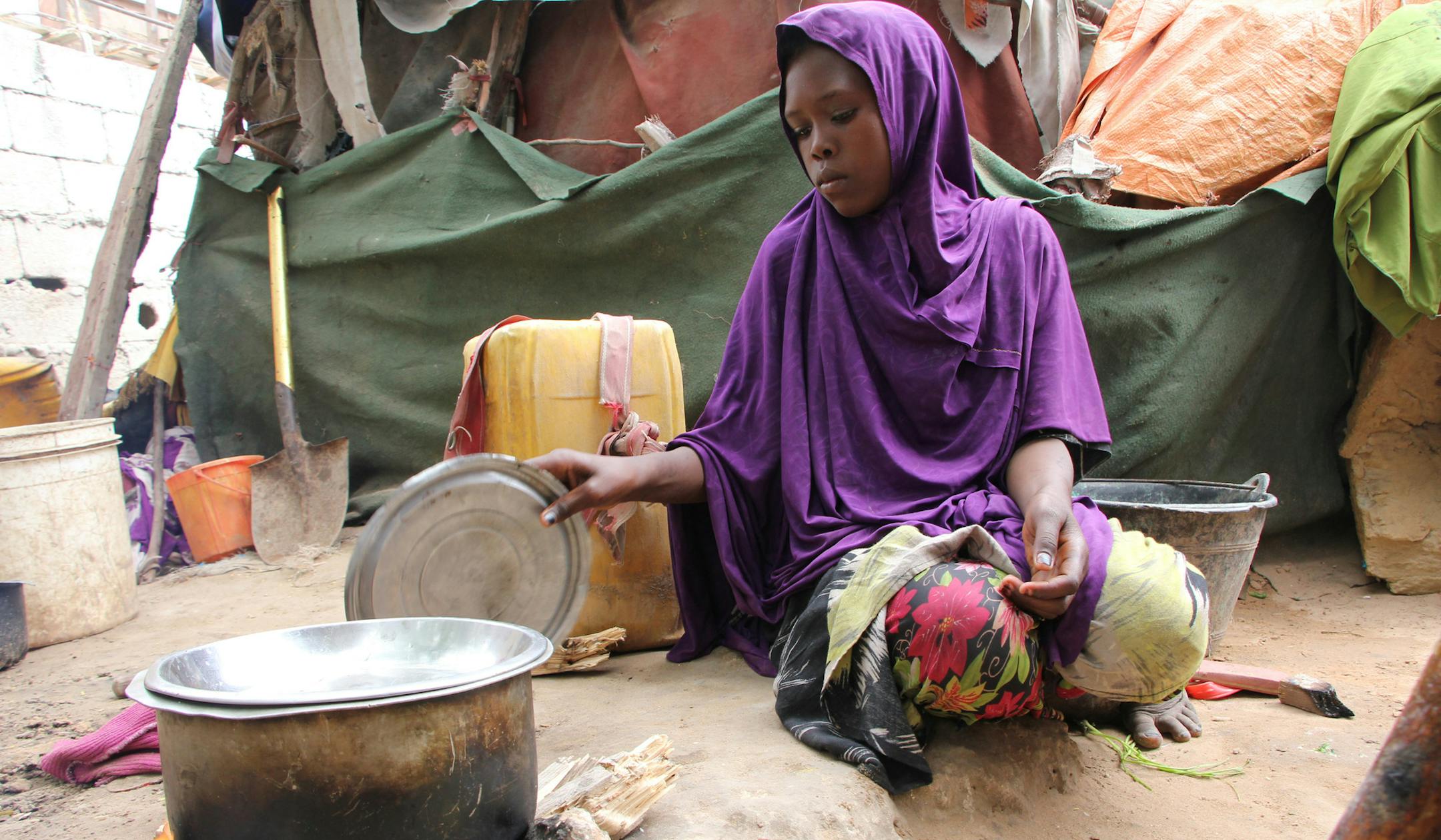Somali young girl cooks food outside their makeshift home inside a refugee camp in Mogadishu, Somalia, Tuesday, Sept. 20, 2016. A new U.N. report says five million people, more than 40 percent of the population in Somalia, are not getting enough food, on the chaotic Horn of Africa. The report released Tuesday says the number of people who are food insecure has increased by 300,000 since February. (AP Photo/Farah Abdi Warsameh)