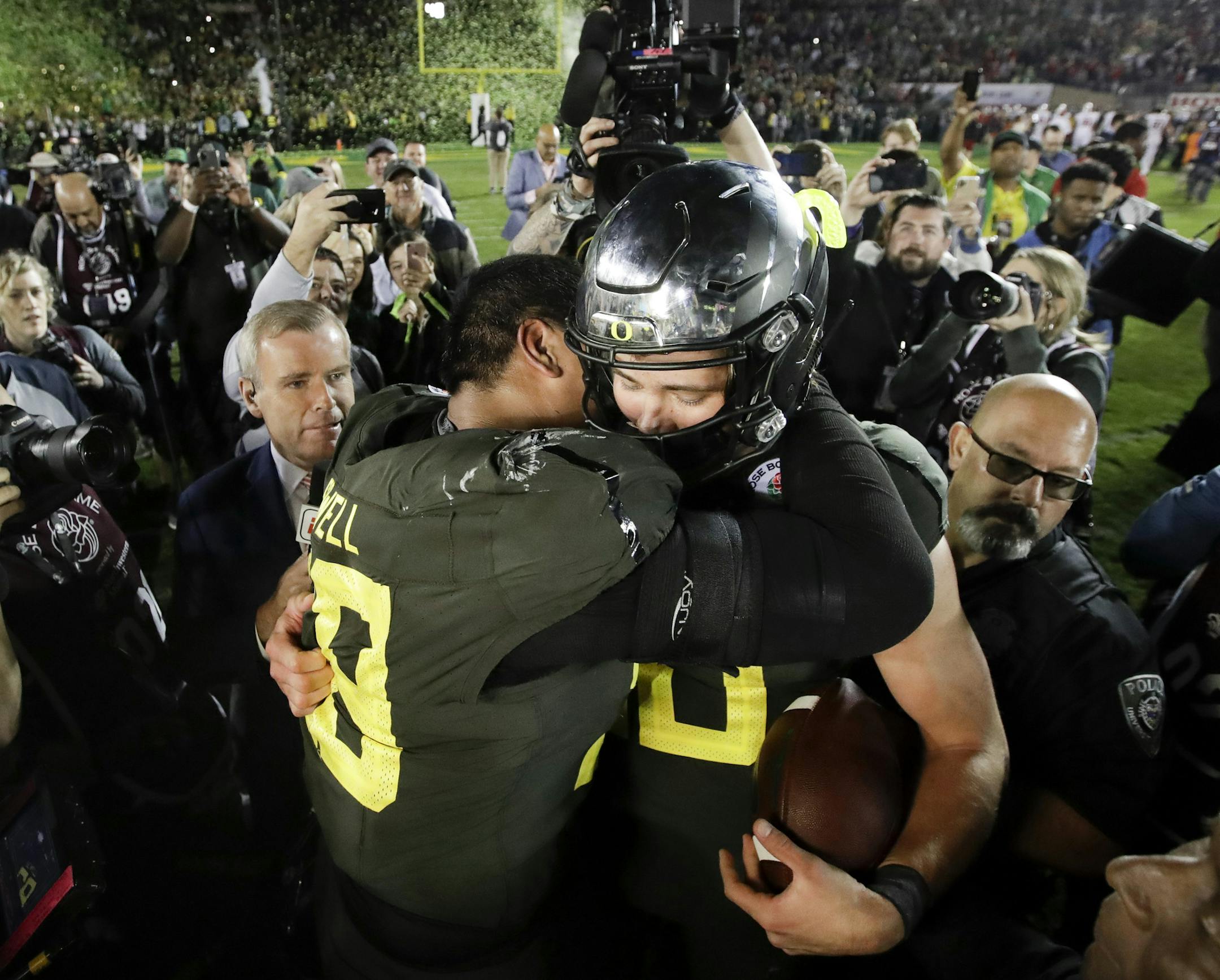 Oregon quarterback Justin Herbert, right, hugs offensive lineman Penei Sewell after their win against Wisconsin in the Rose Bowl NCAA college football game Wednesday, Jan. 1, 2020, in Pasadena, Calif. (AP Photo/Marcio Jose Sanchez)
