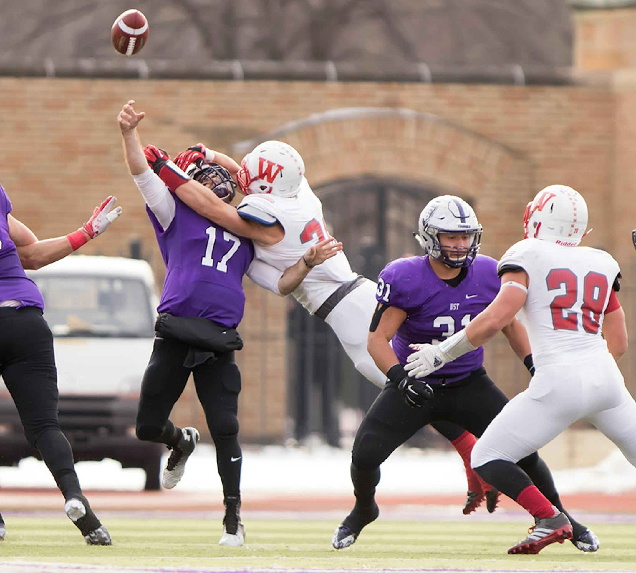 St. Thomas quarterback John Gould (17) gets hit as he throws the ball by Wabash LB Evan Hansen (36) as the University of St. Thomas Tommies hosted the Wabash College Little Giants on December 5, 2015.