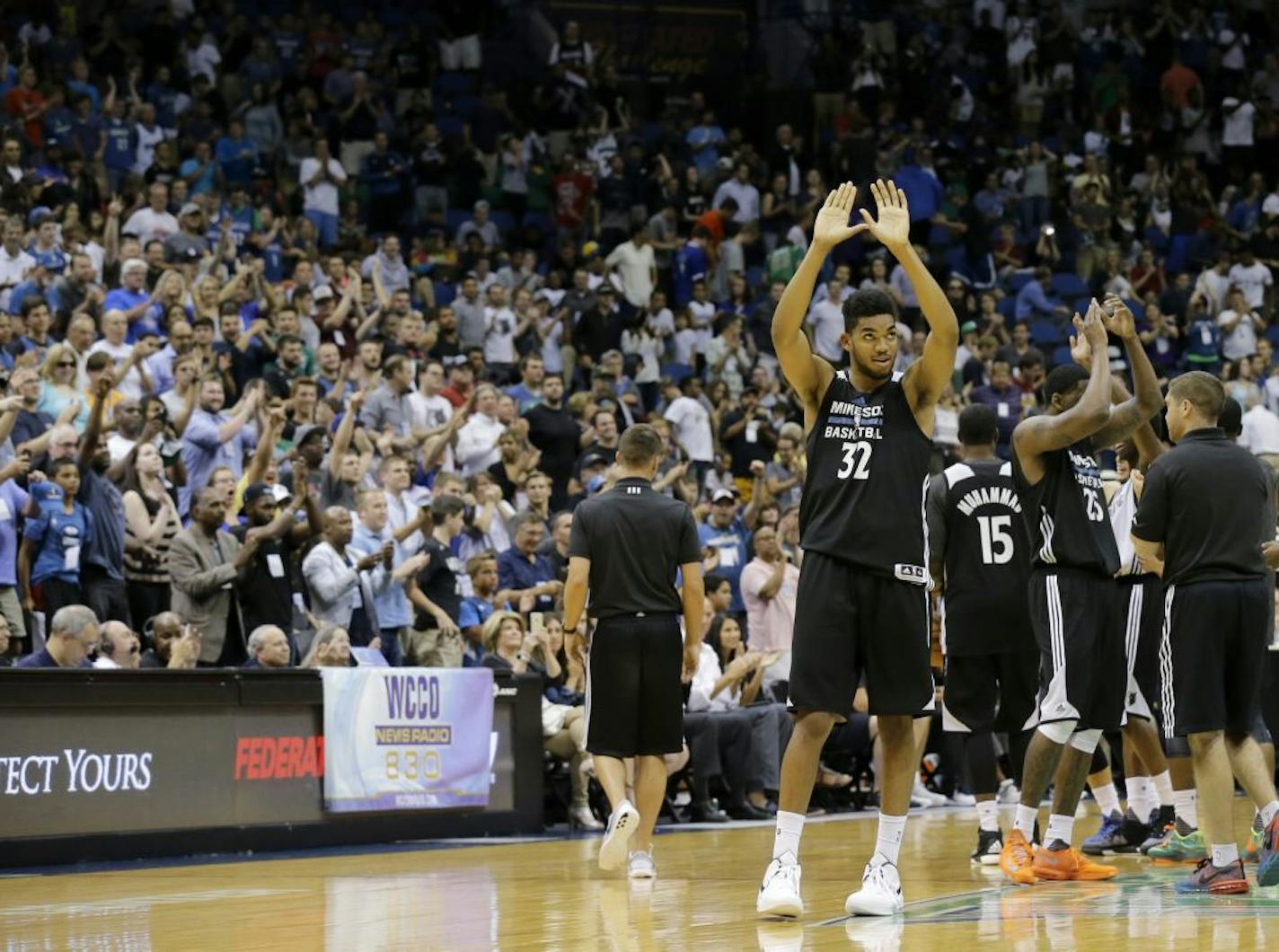 Minnesota Timberwolves center Karl-Anthony Towns (32) and teammates acknowledge the crowd during an NBA basketball scrimmage in Minneapolis, Wednesday, July 8, 2015.