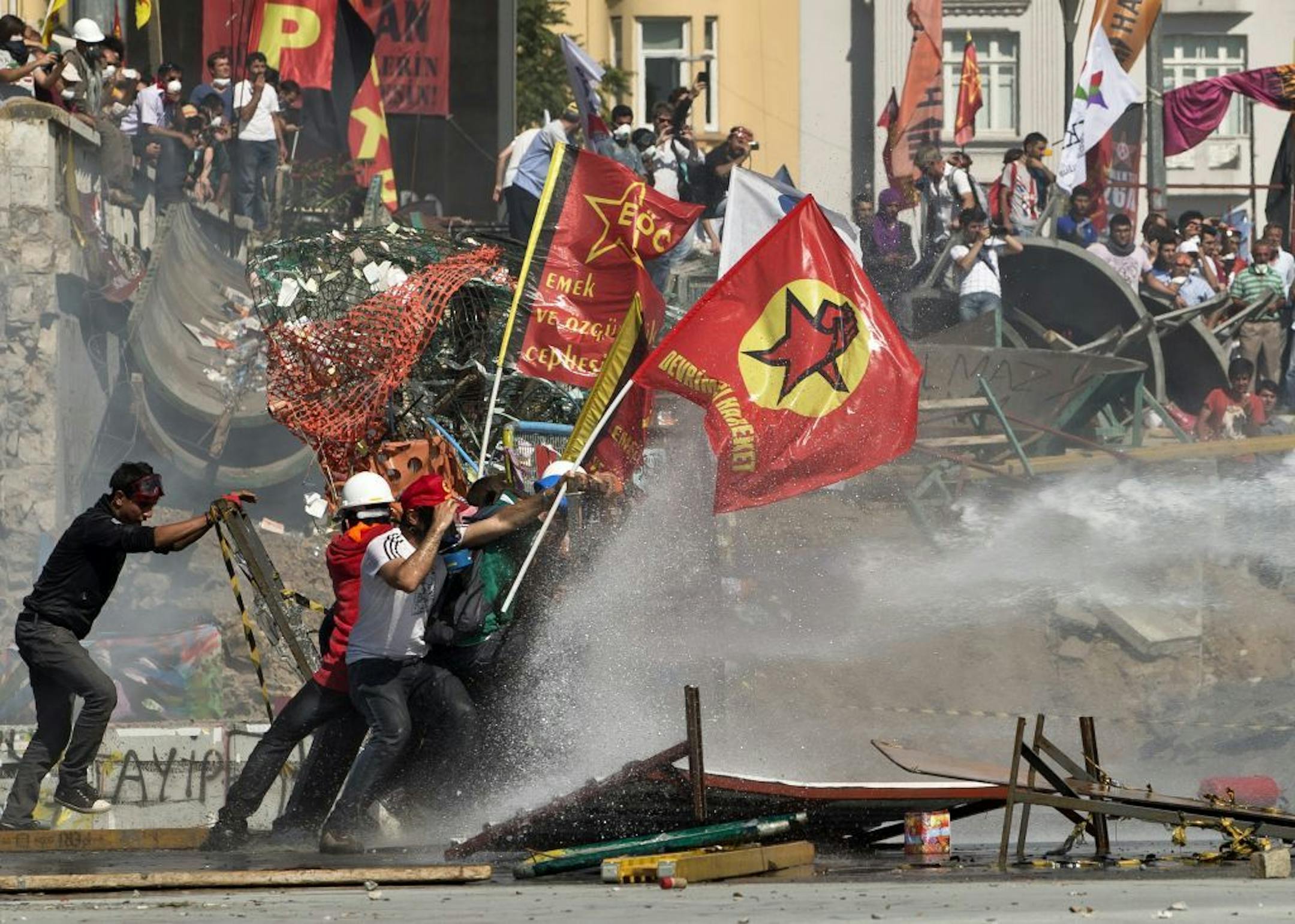 Protesters take cover as a police vehicle fires water canon during clashes at the Taksim Square in Istanbul Tuesday, June 11, 2013.