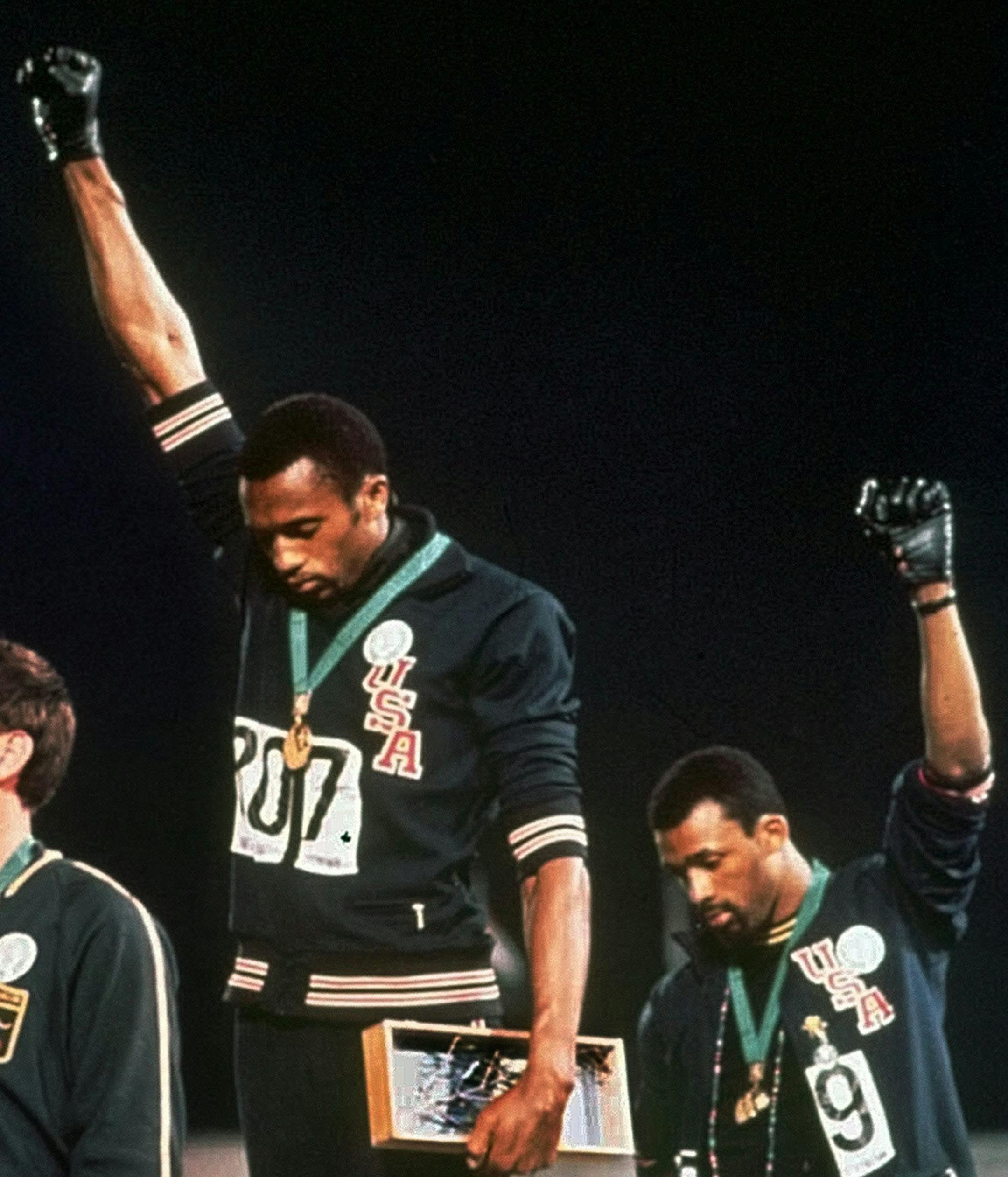 FILe - In this Oct. 16, 1968, file photo, U.S. athletes Tommie Smith, center, and John Carlos stare downward while extending gloved hands skyward during the playing of the Star Spangled Banner after Smith received the gold and Carlos the bronze for the 200 meter run at the Summer Olympic Games in Mexico City. Australian silver medalist Peter Norman is at left. Smith and Carlos, the American sprinters whose raised-fist salutes at the 1968 Olympics are an ageless sign of race-inspired protest, wil