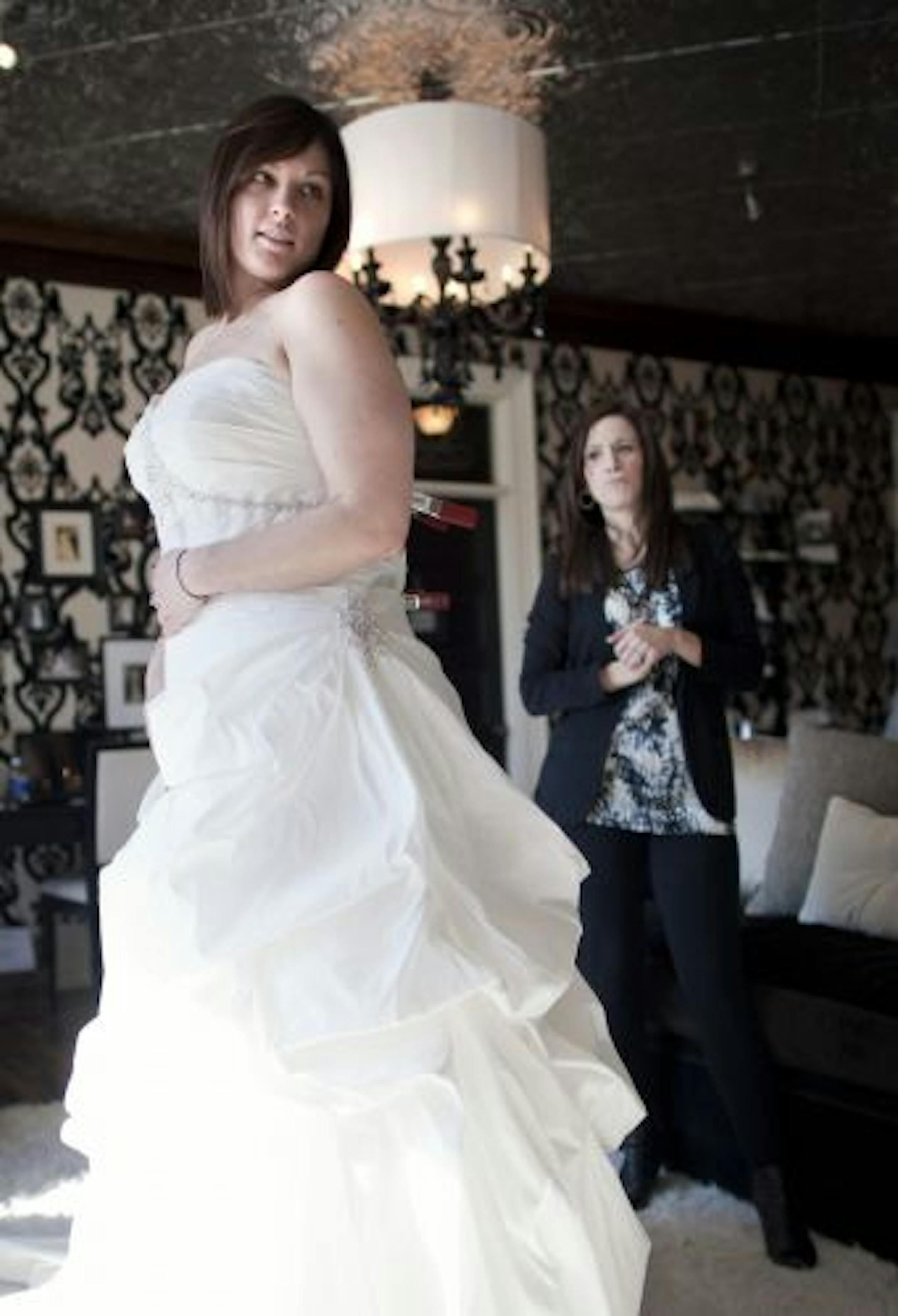 Shayna Clute, owner of Luxe Bridal Couture helped bride Lisa Thompson try on wedding dresses. Luxe caters to plus-sized brides.