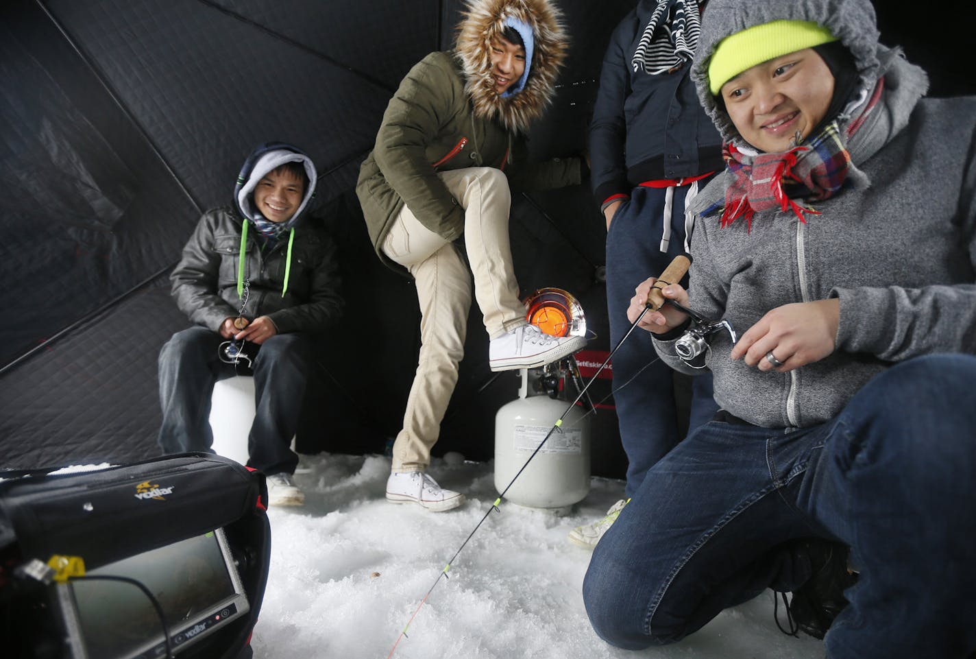 Txu Yang a security guard a Washington High School fished as 17-year-old Htoo Moo warmed his feet. St. Paul Police department took 10 Karen students from Washington High School on a ice fishing trip on Big Marine Lake Monday February 16, 2015 in Scandia, MN. ] Jerry Holt/ Jerry.Holt@Startribune.com