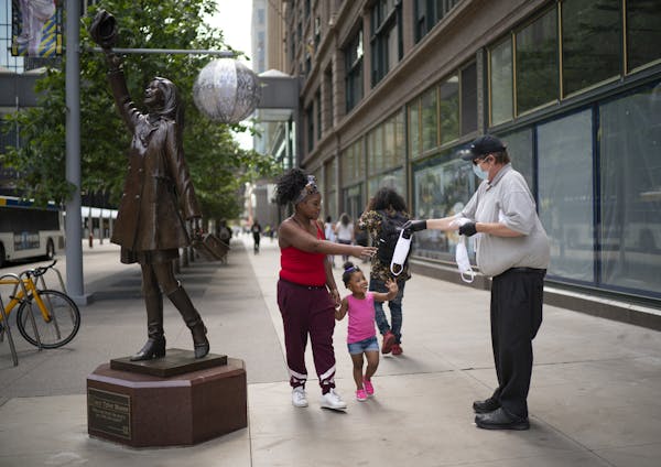 Porcha Lacey, with her daughter, Lyric, took Metro Transit's Tony Dodge up on his offer of a free face mask at the corner of 7th & Nicollet Thursday a