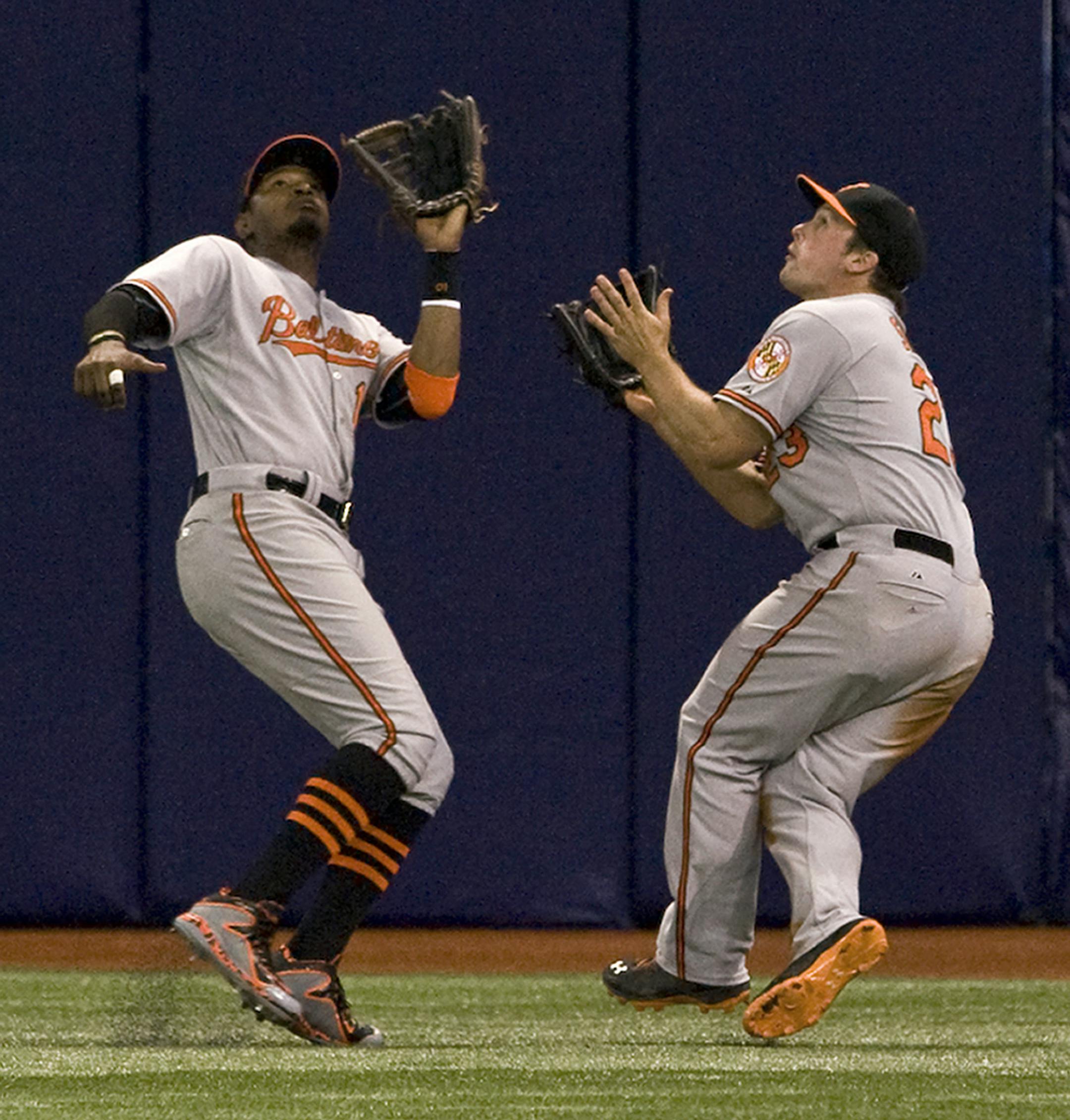 Baltimore Orioles outfielders Adam Jones. left, and Travis Snider narrowly avoid a collision while chasing down a fly ball hit by Tampa Bay Rays' Logan Forsythe during the eighth inning of a baseball game, Tuesday, April 7, 2015, in St. Petersburg, Fla. Jones made the catch for the out. (AP Photo/Steve Nesius)