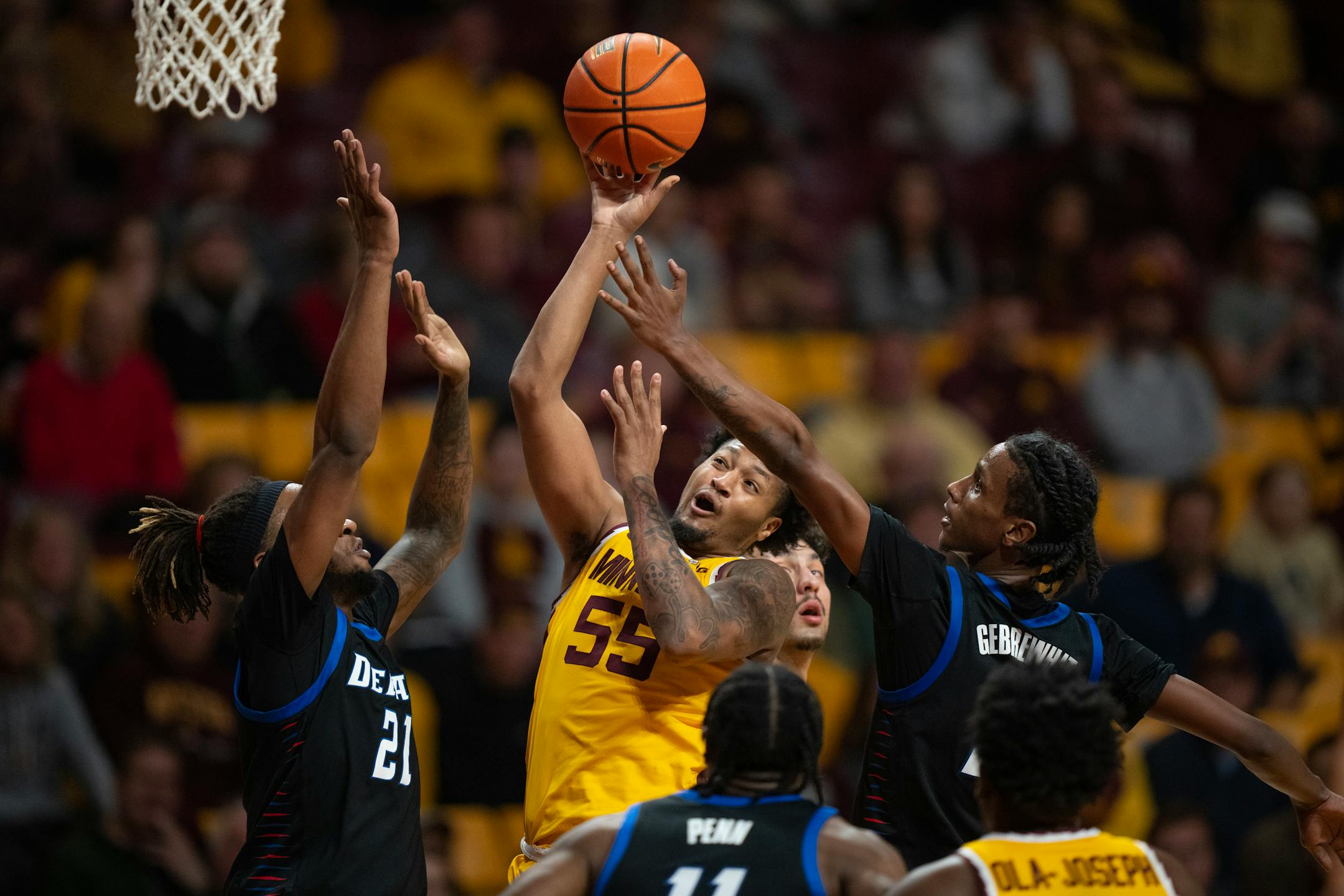 Minnesota Gophers guard Ta'lon Cooper (55) shot while defended by the DePaul duo of  forward Da'Sean Nelson (21) and Philmon Gebrewhit (5) in the second half.