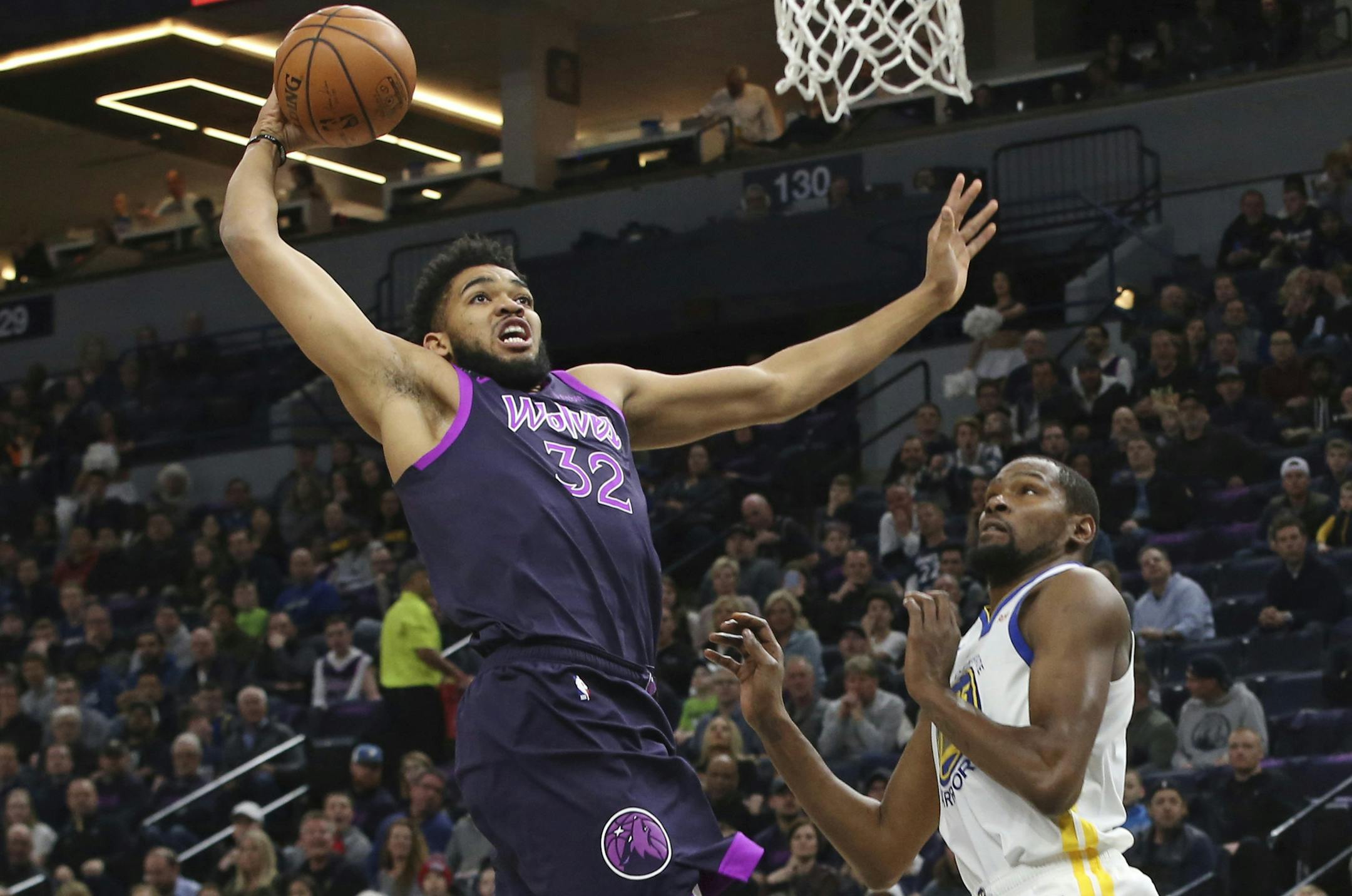 CORRECTS TO KEVIN DURANT, NOT DRAYMOND GREEN - Minnesota Timberwolves' Karl-Anthony Towns, left, lays up as Golden State Warriors' Kevin Durant watches in the first half of an NBA basketball game Tuesday, March 19, 2019, in Minneapolis. (AP Photo/Jim Mone)