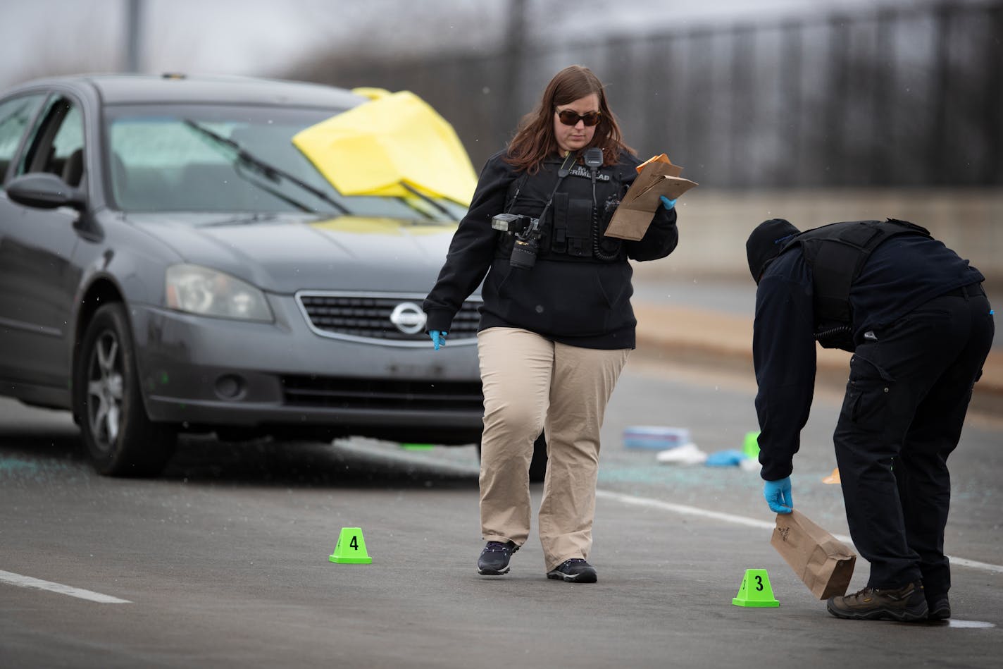 Members of the crime lab collected evidence from around the car were one man was shot to death and another wounded on 7th St. N heading into downtown Minneapolis on Sunday.