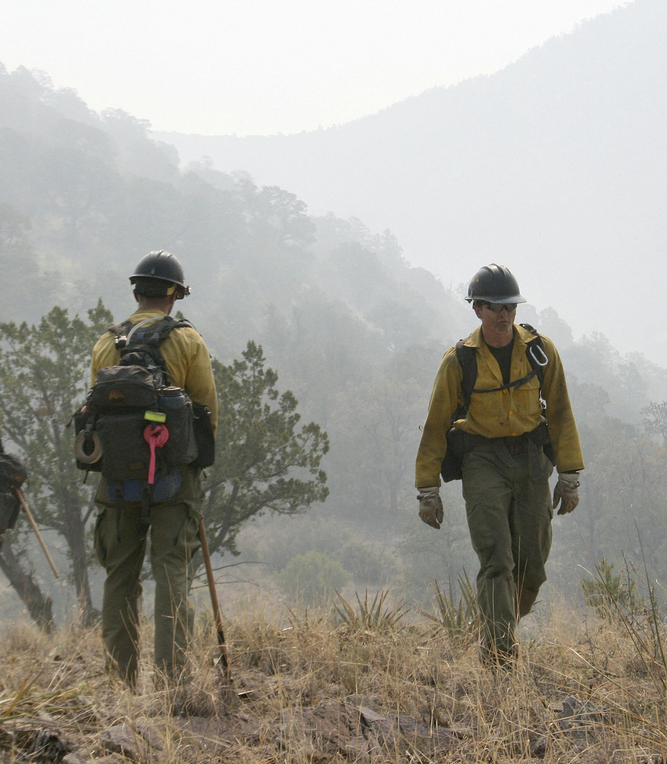 FILE - In this June 2, 2012 file photo, firefighters from the Granite Mountain Hotshots of Prescott, Ariz. cut a fire line along a mountain ridge in the Gila National Forest outside Mogollon, N.M. On Sunday, June 30, 2013, a fast-moving wildfire killed 19 firefighters from this group after the blaze raced through the central Arizona town of Yarnell, about 85 miles northwest of Phoenix. (AP Photo/U.S. Forest Service, Tara Ross) ORG XMIT: MIN2013071215180458