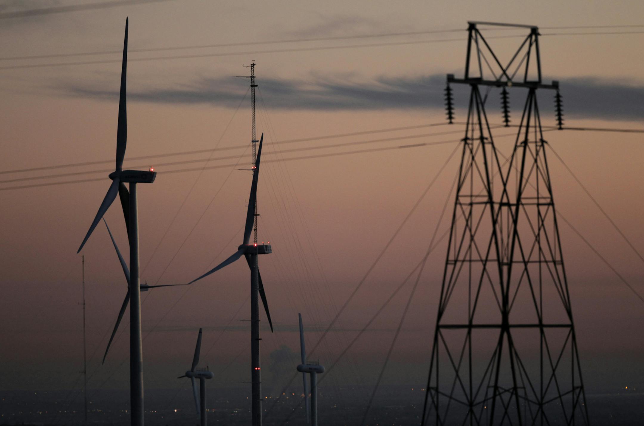 FILE - This Nov. 3, 2012 file photo shows wind turbines, alongside an electrical tower, at the National Wind Technology Center, run by the U.S. Department of Energy, outside Boulder, Colo. Two new studies suggest that Wyoming and Colorado both would benefit by coordinating development of wind energy and power lines to carry that electricity. One study by the University of Wyoming's Wind Research Center shows that Wyoming's wind is stronger than the wind in Colorado. Wyoming's wind also tends to