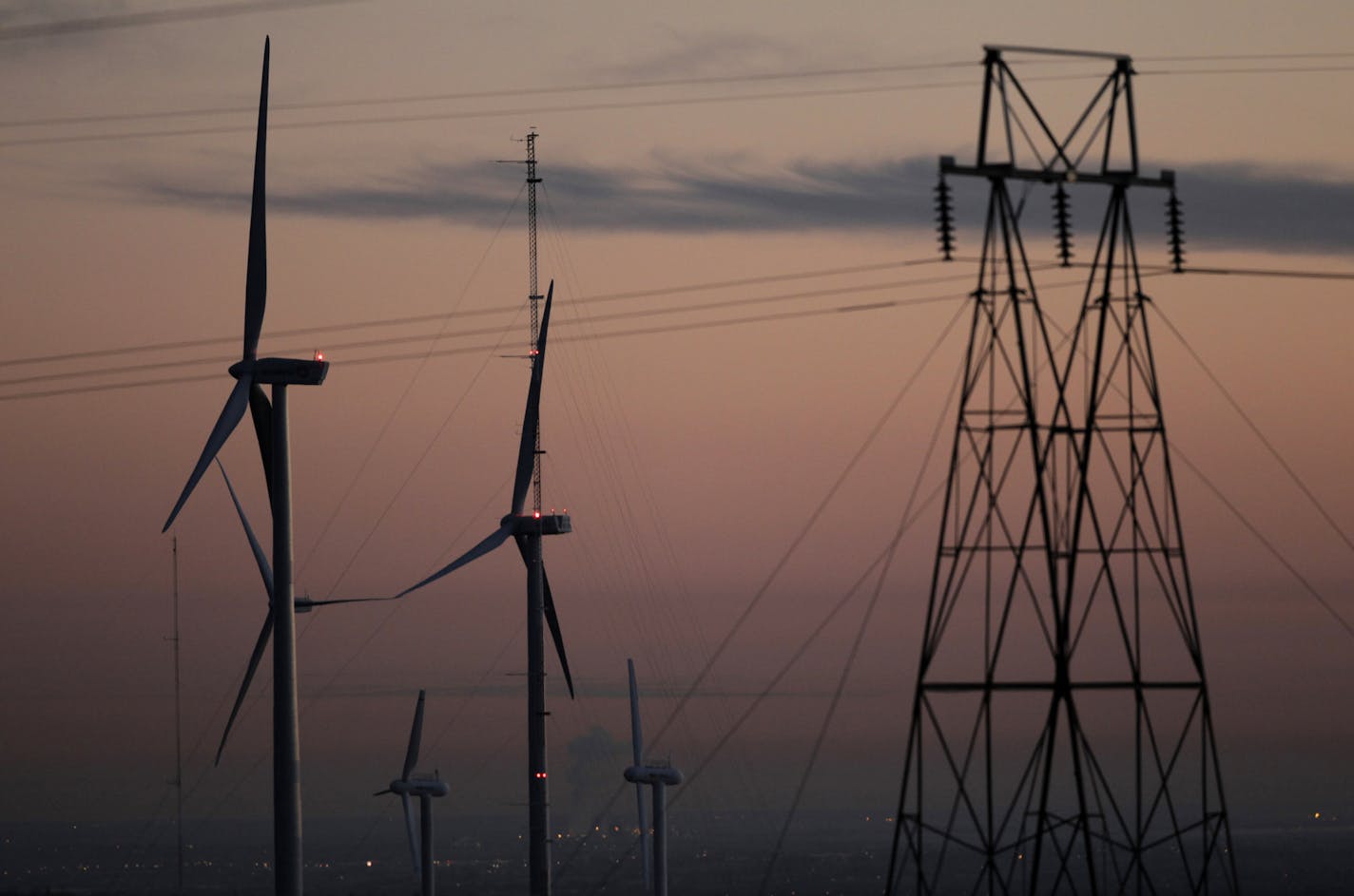 FILE - This Nov. 3, 2012 file photo shows wind turbines, alongside an electrical tower, at the National Wind Technology Center, run by the U.S. Department of Energy, outside Boulder, Colo. Two new studies suggest that Wyoming and Colorado both would benefit by coordinating development of wind energy and power lines to carry that electricity. One study by the University of Wyoming's Wind Research Center shows that Wyoming's wind is stronger than the wind in Colorado. Wyoming's wind also tends to