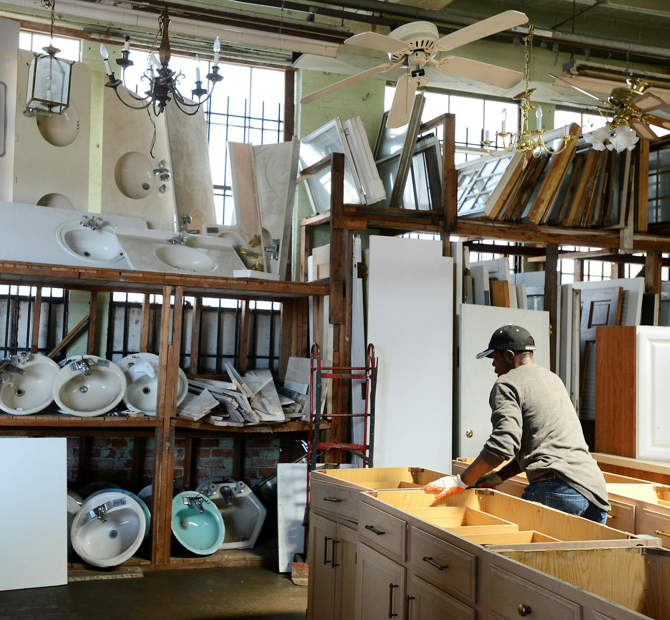 Warehouse personnel and field worker Michael Leitner moves a kitchen cabinet into place at the Architectural Salvage Warehouse, Tuesday, May 13, 2014. Detroit plans to start work soon on a pilot project to rescue and sell parts of deteriorating homes before demolishing them. The deconstruction project will solicit bids from teams to salvage reusable flooring, fixtures and moldings in 10 vacant buildings in one city neighborhood. (AP Photo/The Detroit News, Robin Buckson) DETROIT FREE PRESS OUT;