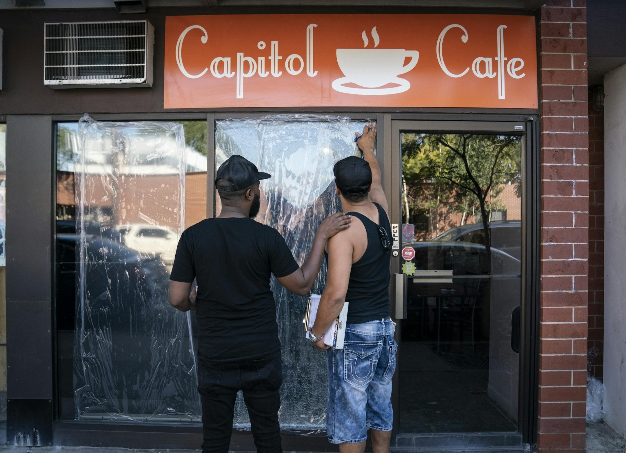 Burhan Elmi, co-owner of the cafe, left, chatted with John Torgeson, right, who works in emergency glass services, who had come to measure the windows and give him a quote for the repair. Two large windows at the Capitol Cafe and several other store windows were damaged along Franklin Avenue by a vandal recently in Minneapolis, Minn., on Thursday, September 19, 2019.