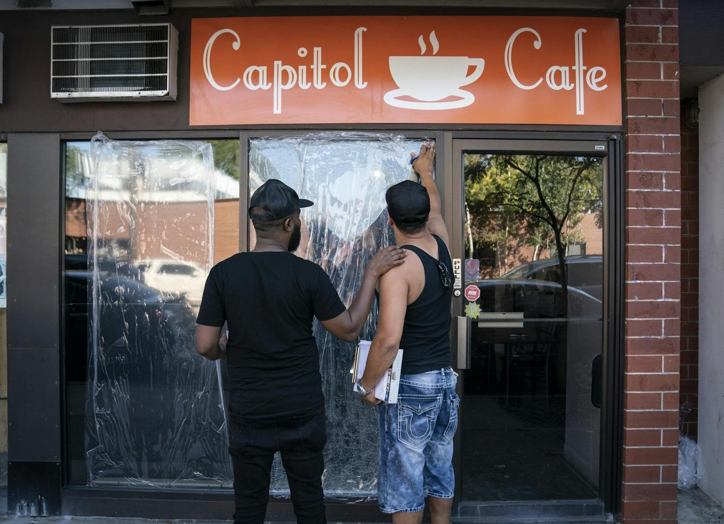 Burhan Elmi, co-owner of the cafe, left, chatted with John Torgeson, right, who works in emergency glass services, who had come to measure the windows and give him a quote for the repair. Two large windows at the Capitol Cafe and several other store windows were damaged along Franklin Avenue by a vandal recently in Minneapolis, Minn., on Thursday, September 19, 2019.