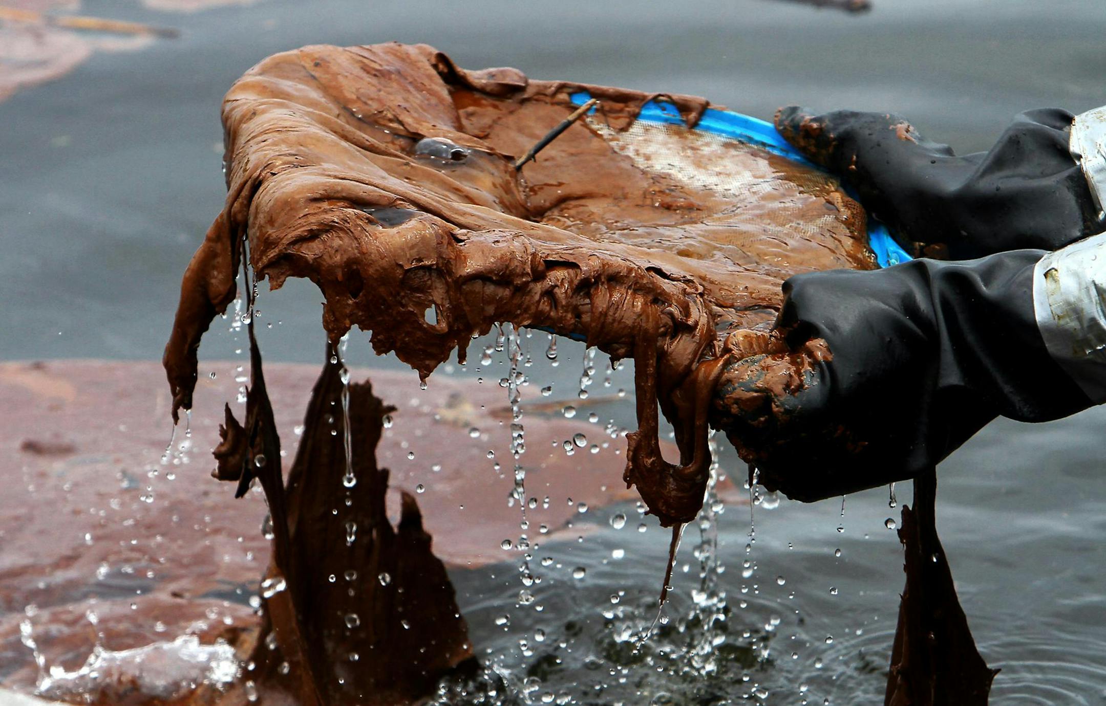 A cleanup worker lifts a handheld skimmer full of weathered oil from the waters near the boat ramp adjacent to Ken Combs Pier in Gulfport, Miss., on July 1 2010. The City of Gulfport closed the boat ramp a day earlier and crews were out in force to clean up large amounts of oil that had contaminated the stone jetties and surrounding areas of the pier. (Amanda McCoy/Biloxi Sun Herald/TNS)