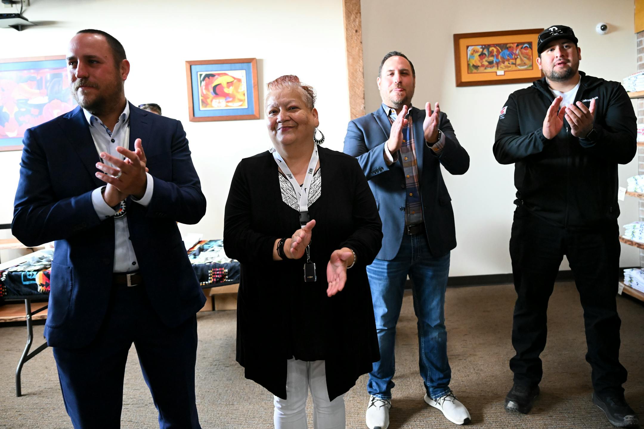 Red Lake Nation Tribal Council Member Michelle Barrett-Cobenais applauds the state's first recreational marijuana sale as she stands between brothers Grant Johnson, left, and Blake Johnson, who traveled to support Red Lake as representatives from the Prairie Island Indian Community, Tuesday, Aug. 1, 2023 at NativeCare in Red Lake, Minn.