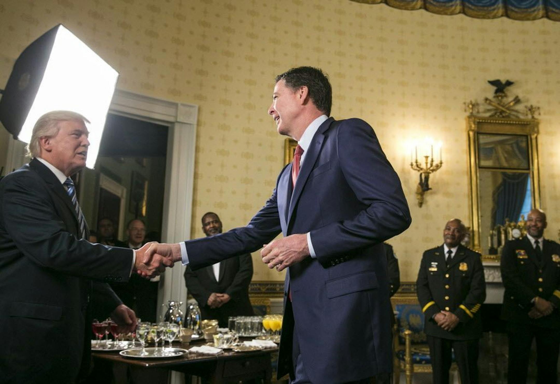 James Comey, the director of the FBI, shakes hands with President Donald Trump at a reception for law enforcement officers and first responders who helped at the inauguration, in the Blue Room of the White House in Washington, Jan. 22, 2017.