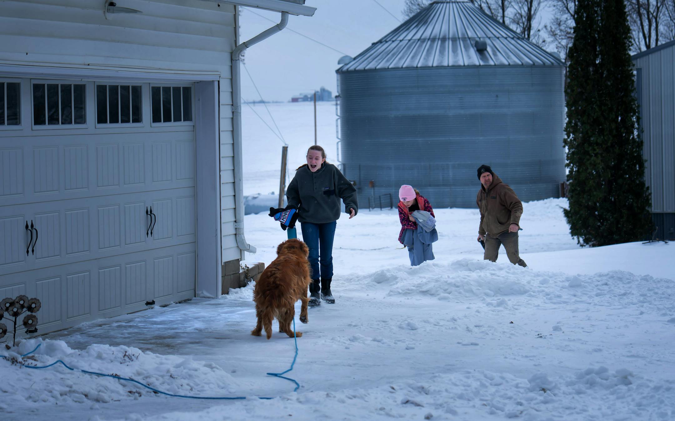 Ben Johnson along with daughters Talia, 14, and Ellie, 9, returned from the pig barns where an unexpected snow day off from school gave them time to vaccinate a few thousand pigs in the morning. Talia greeted the family dog Parker, who was waiting for them.