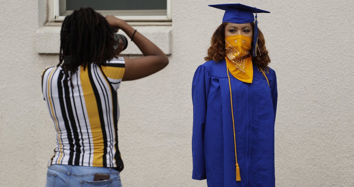 Anderson High School senior Teyaja Jones, right, poses in her cap and gown and a bandana face cover, Tuesday, May 5, 2020, in Austin, Texas. Texas' stay-at-home orders due to the COVID-19 pandemic have expired and Texas Gov. Greg Abbott has eased restrictions on many businesses that have now opened, but school buildings remain closed. (AP Photo/Eric Gay)