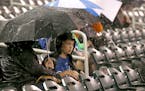 A young Kansas City Royals fan takes cover under an umbrella as a rain delay is called during the third inning of a baseball game between the Royals a