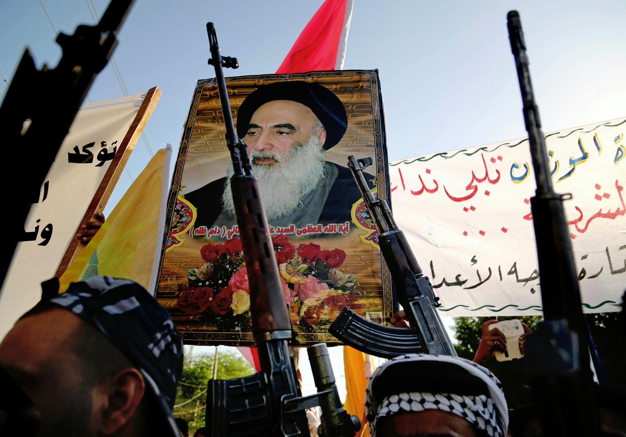 Shiite tribal fighters carry a poster of Shiite spiritual leader Grand Ayatollah Ali al-Sistani, as they raise their weapons chanting slogans against the al-Qaida-inspired Islamic State of Iraq and the Levant (ISIL) in Basra, Iraq's second-largest city, 340 miles (550 kilometers) southeast of Baghdad, Iraq, Monday, June 16, 2014. Sunni militants captured a key northern Iraqi town along the highway to Syria early on Monday, compounding the woes of Iraq's Shiite-led government a week after it lost