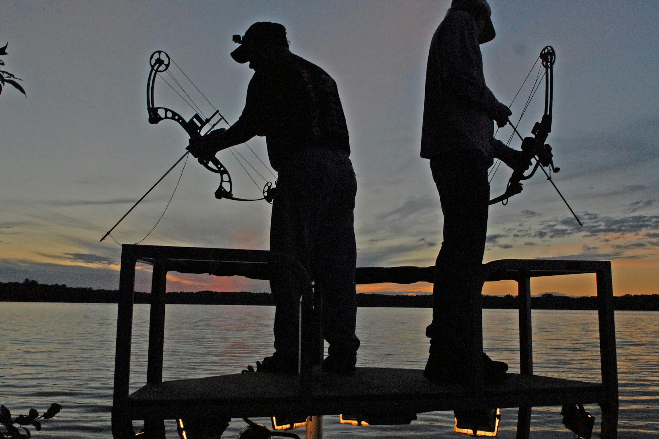 Pete Luke, left, and Cole Anderson prowl a lake near Princeton, Minn., on Wednesday night, while bowfishing for carp. The sport has become increasingly popular since night bowfishing was legalized beginning in 2008.