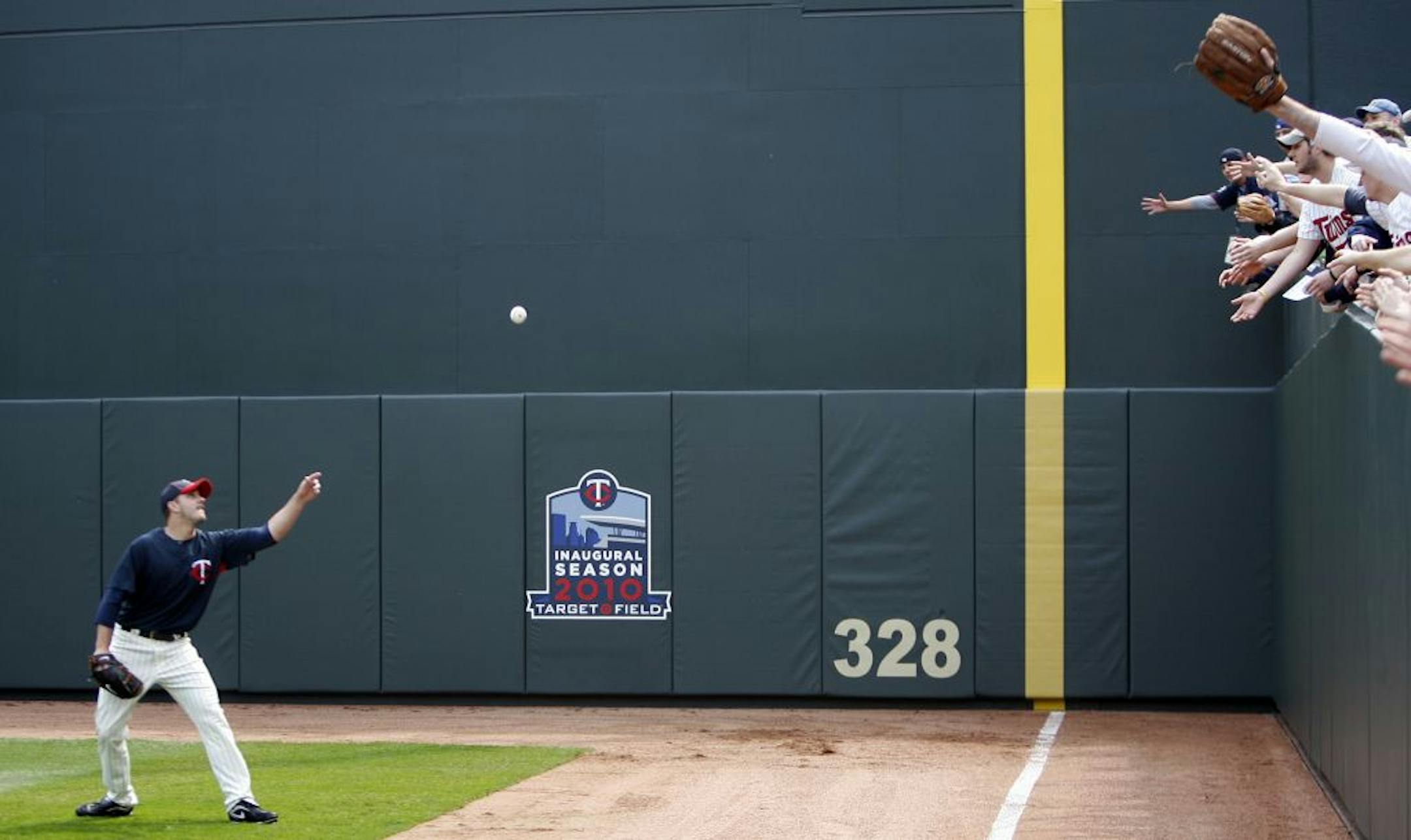 Fans reach for a ball as they watched batting practice Monday at Target Field.