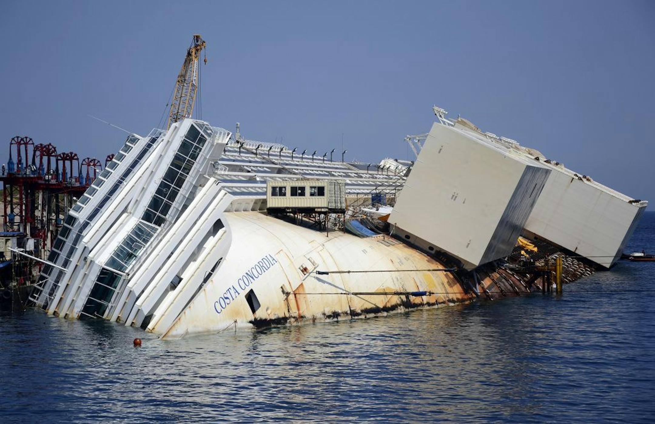 The Costa Concordia cruise ship lies on its side in the Tuscan Island of Isola del Giglio, Monday, July 15, 2013. Salvage crews are working against time to right and remove the shipwrecked Costa Concordia cruise ship, which is steadily compressing down on itself from sheer weight onto its granite seabed perch off the Tuscan island of Giglio. Salvage master Nick Sloane said Monday that the Concordia has compressed some 3 meters (10 feet) since it came to rest on the rocks Jan. 13, 2012 after ramm