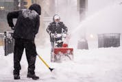 Luis Cabrera and Carlos Toro, left to right, cleared snow on the sidewalk in front of the Butcher’s Tale on Hennepin Avenue on Thursday in downtown 