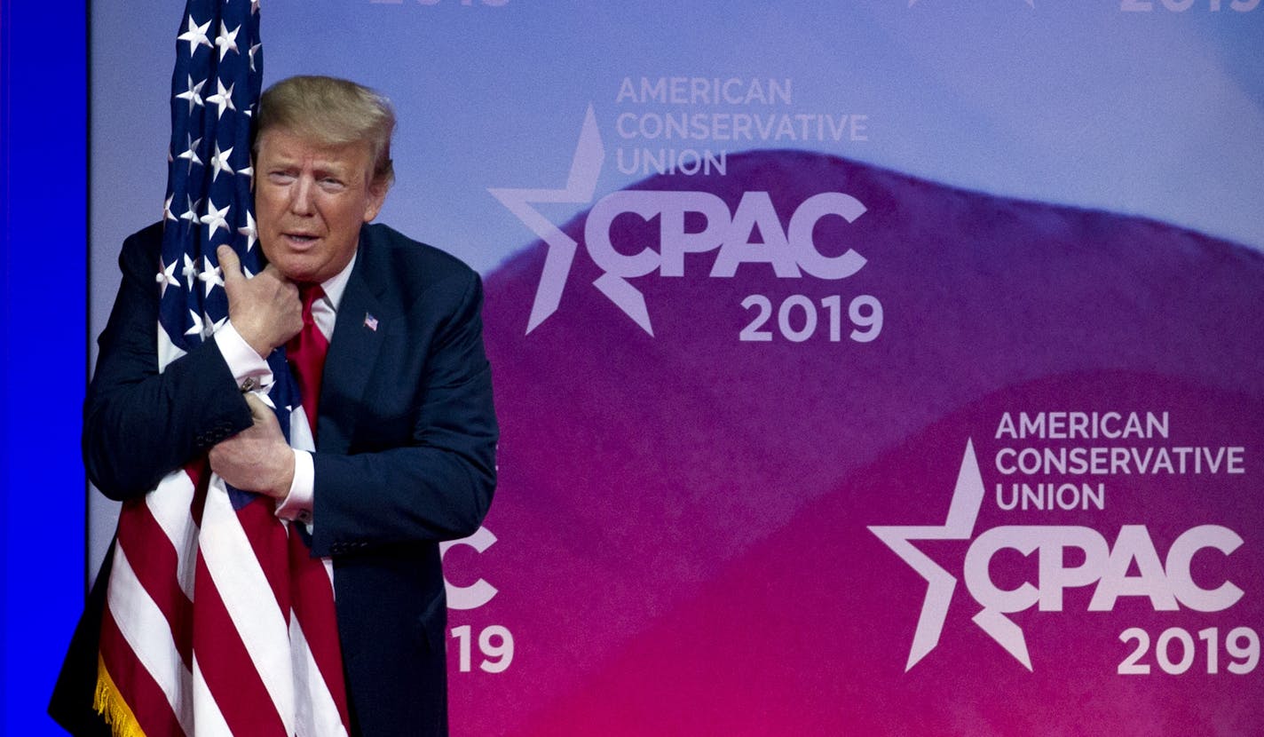 President Donald Trump hugs the American flag as he arrives to speak at Conservative Political Action Conference, CPAC 2019, in Oxon Hill, Md., Saturday, March 2, 2019. (AP Photo/Jose Luis Magana)