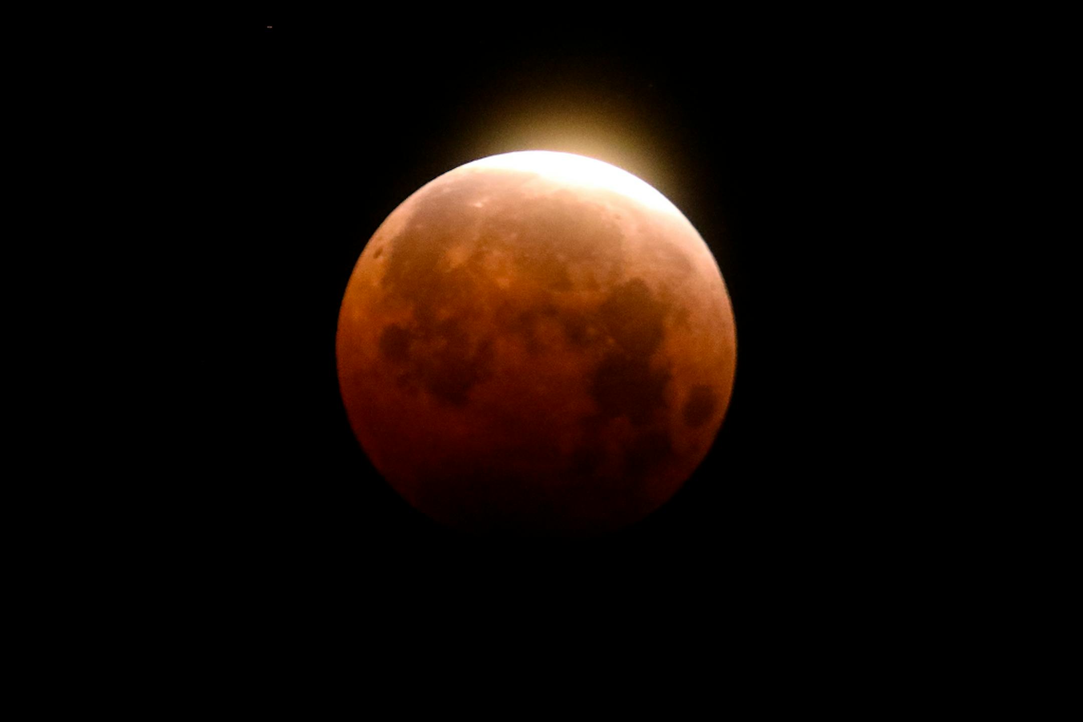 FILE - Light shines from a total lunar eclipse over Santa Monica Beach in Santa Monica, Calif., Wednesday, May 26, 2021. A total lunar eclipse will grace the night skies this weekend, providing longer than usual thrills for stargazers across North and South America. The celestial action unfolds Sunday night, May 15, 2022 into early Monday morning, with the moon bathed in the reflected red and orange hues of Earth's sunsets and sunrises for about 1 1/2 hours, the longest totality of the decade. It will be the first so-called blood moon in a year.(AP Photo/Ringo H.W. Chiu)