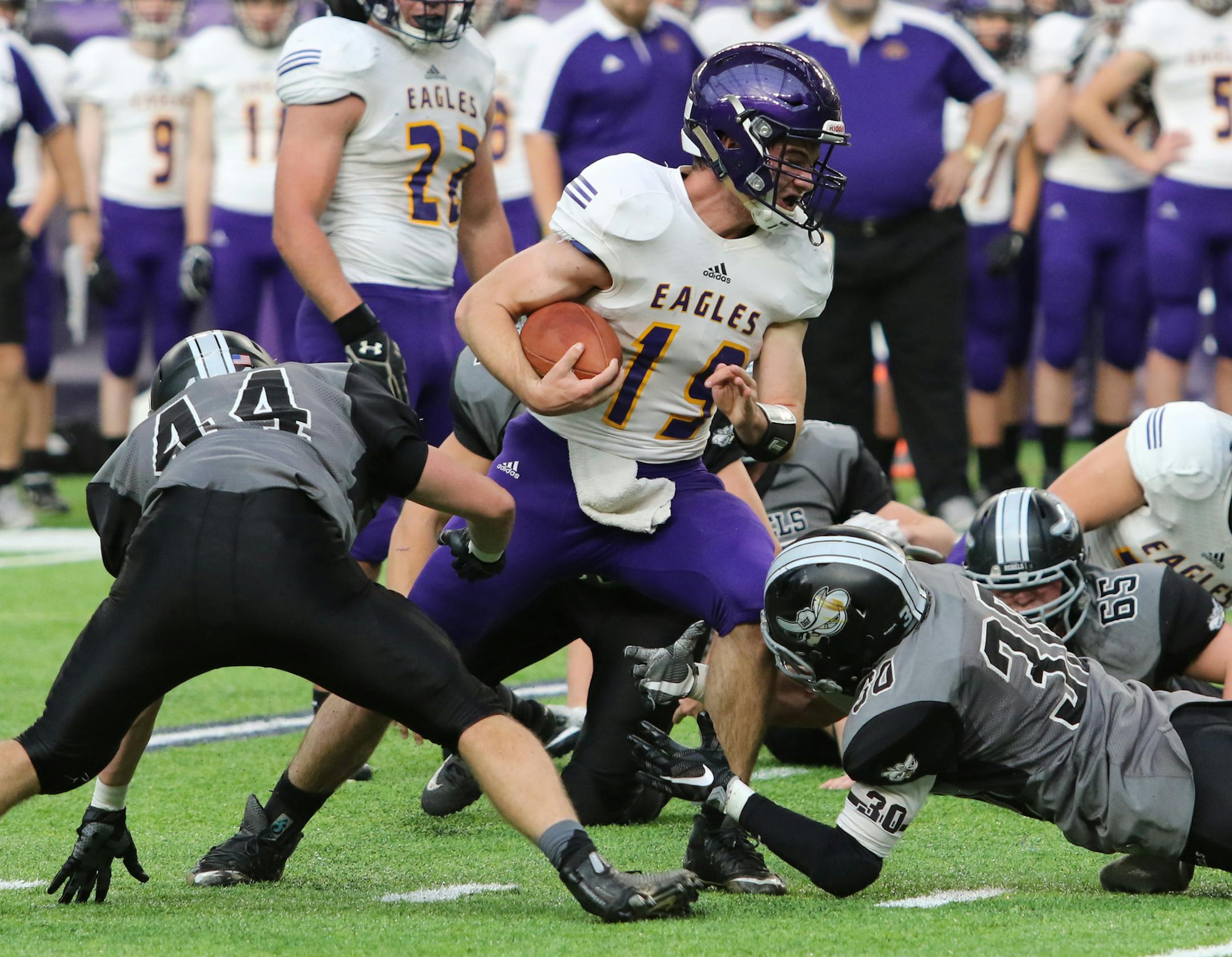 Rochester Lourdes quarterback Noah Hillman tried to run through tackling attempts by Dilworth-Glyndon-Felton's Brandon Ciak (44) and Ryan Poehls (30).