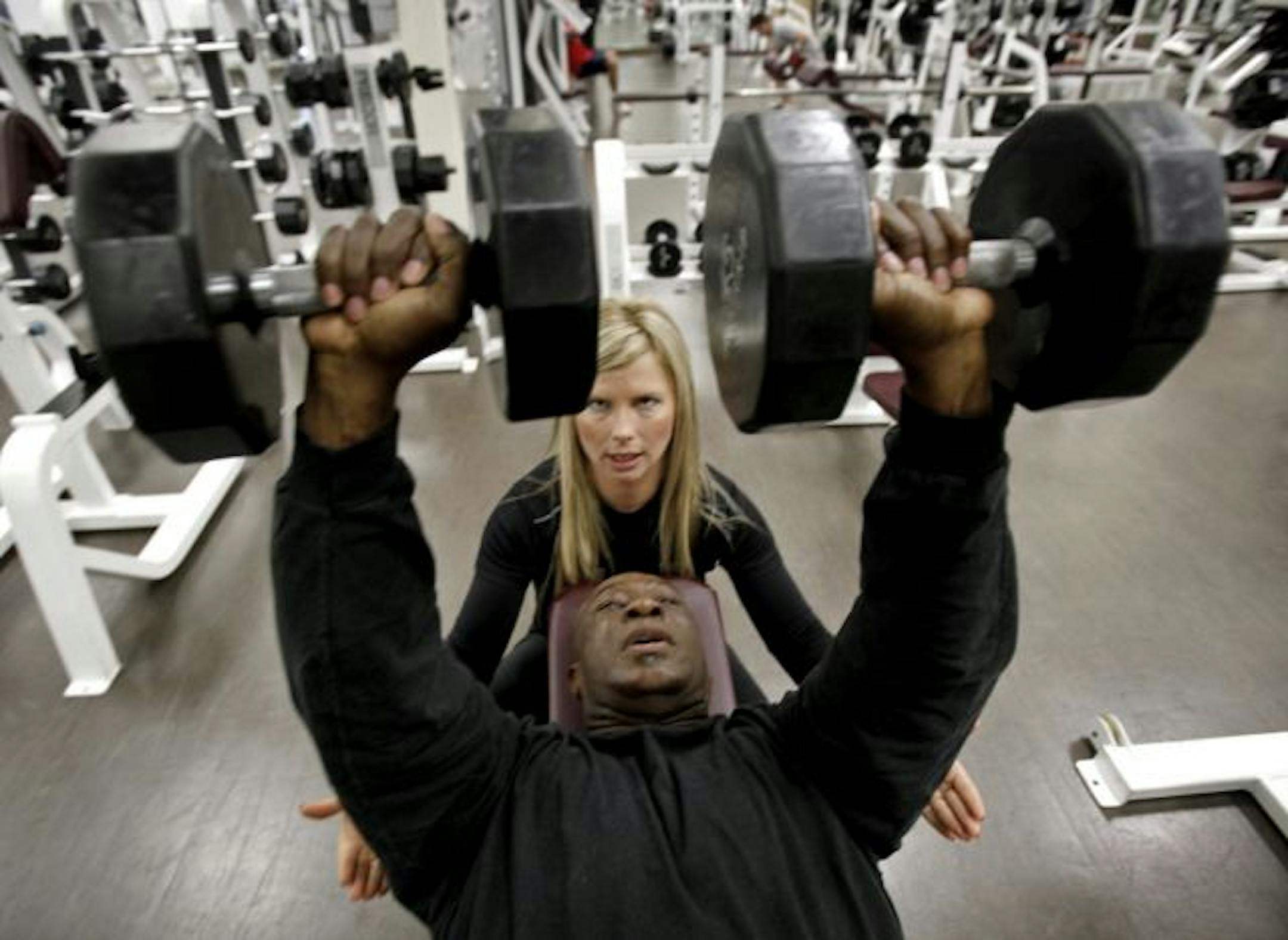 Trainer Tiffany Hoikka gives O'Neal Hampton feedback as he lifts weights.