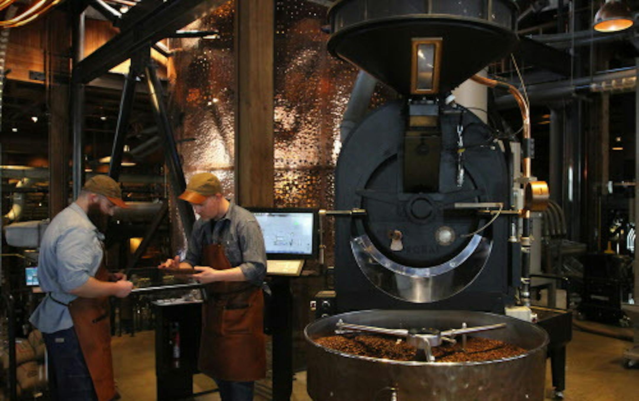 Brandon Cohen, left, roaster operator, and Shawn Sidey, master roaster, check Sitio Baixadao coffee as it's roasted at Starbucks Reserve Roastery. Beans roast at 430 degrees for about 13 minutes, then swirl for five minutes in a cooling tray. (Alan Berner/Seattle Times/TNS) ORG XMIT: 1167437
