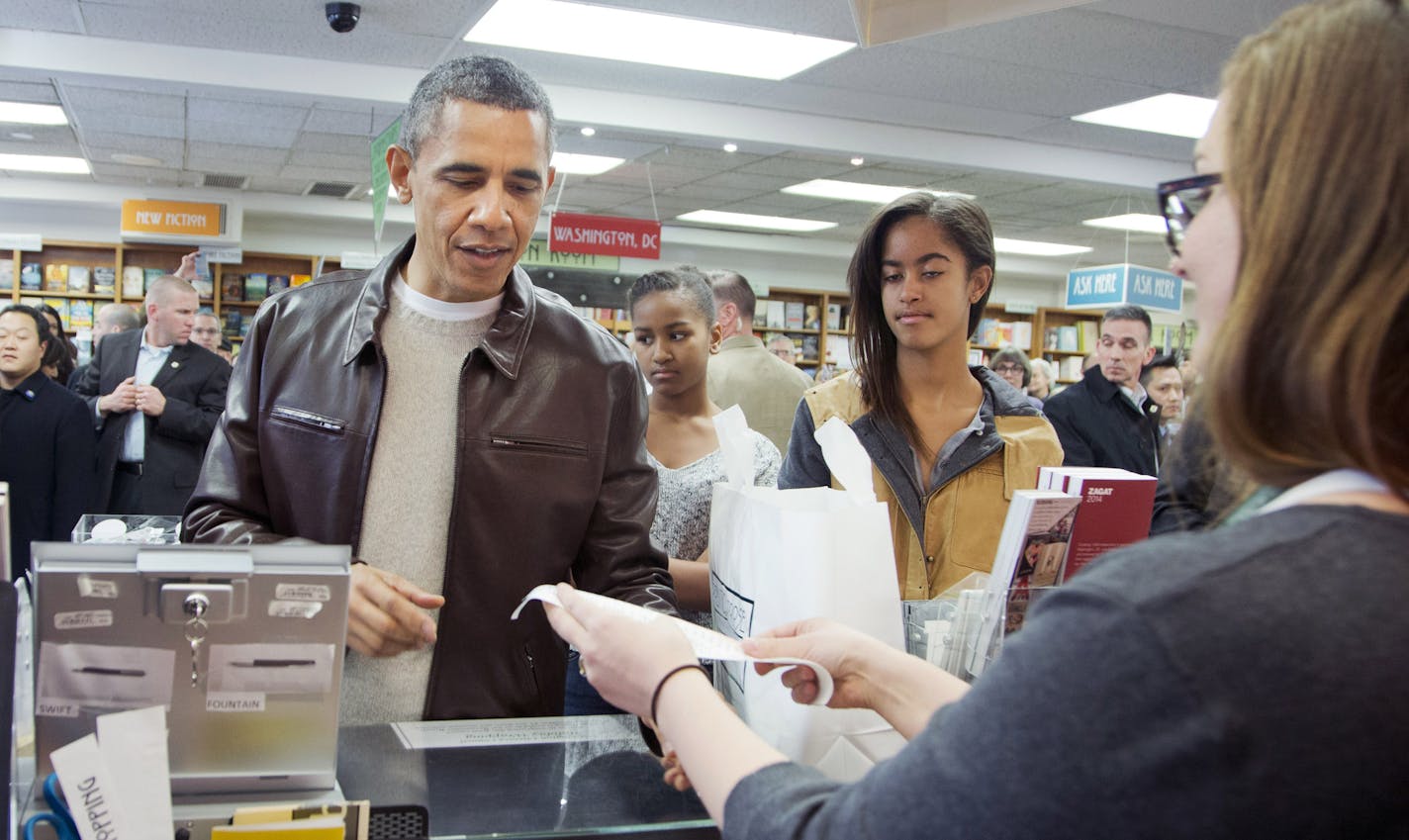 President Barack Obama, with daughters Sasha, center, and Malia, pays for his purchase the the local bookstore Politics and Prose in northwest Washington, Saturday, Nov. 30, 2013. (AP Photo/Manuel Balce Ceneta) ORG XMIT: WHMC101