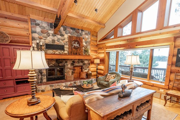 Windows let ample light into the Ely log home while providing vistas of the woods and Burntside Lake. A stone wood-burning fireplace keeps things cozy