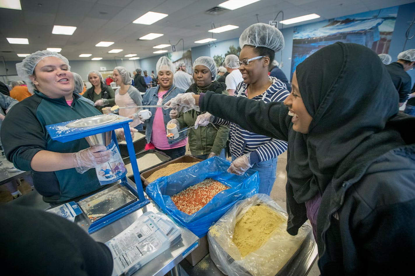 Kadra Mohamed, right, worked alongside Humboldt High School teenage girls that she mentored throughout the school year for a trip to Feed My Starving Children. The girls find comfort and trust in St. Paul's first female Somali police officer.