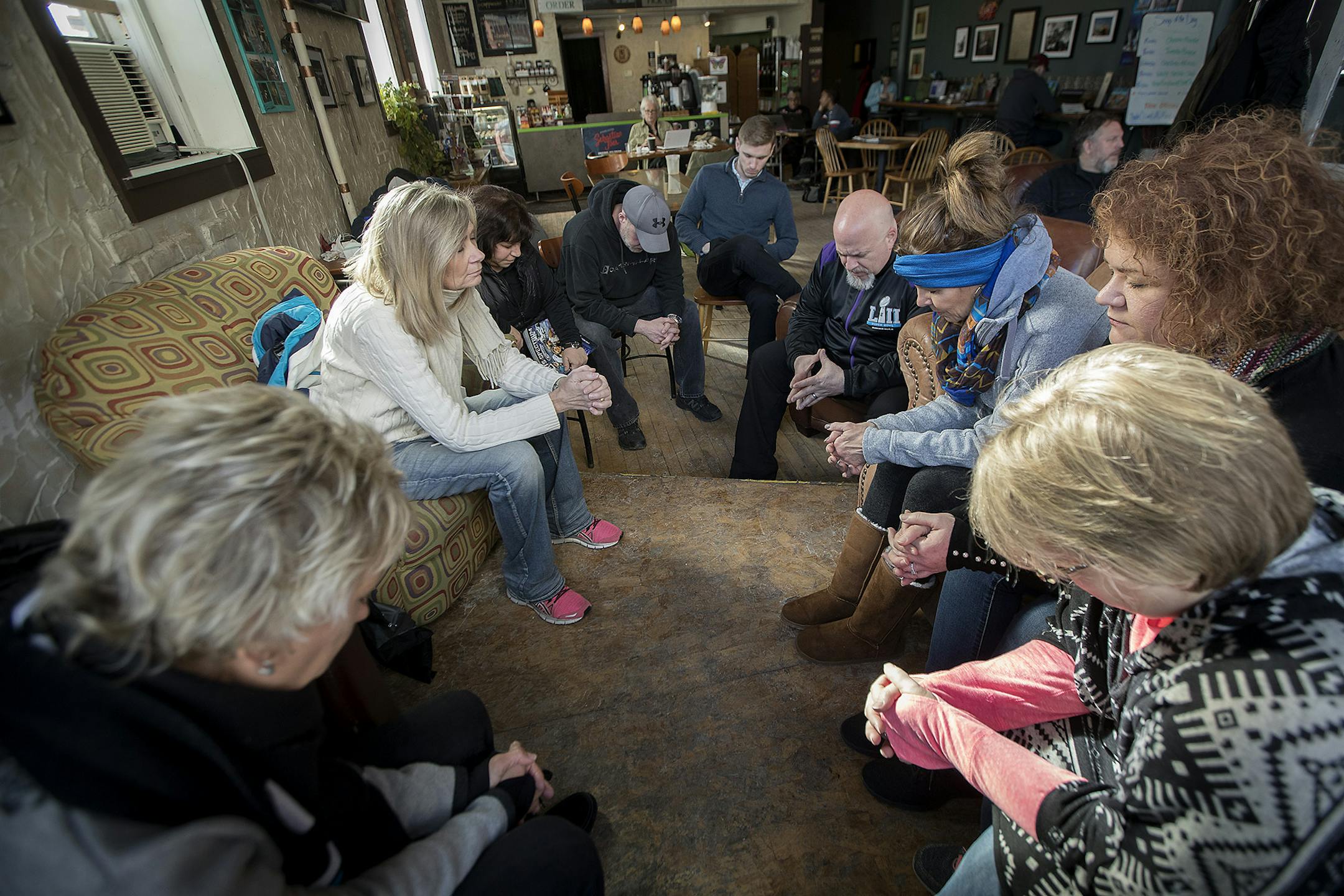 John Steger, on right, led a prayer group in prayer before they organized at Jaur Cafe coffee shop Friday in Minneapolis. The church outreach group organized to hand out the Sports Spectrum magazine to people at Super Bowl Live on Nicollet Mall.