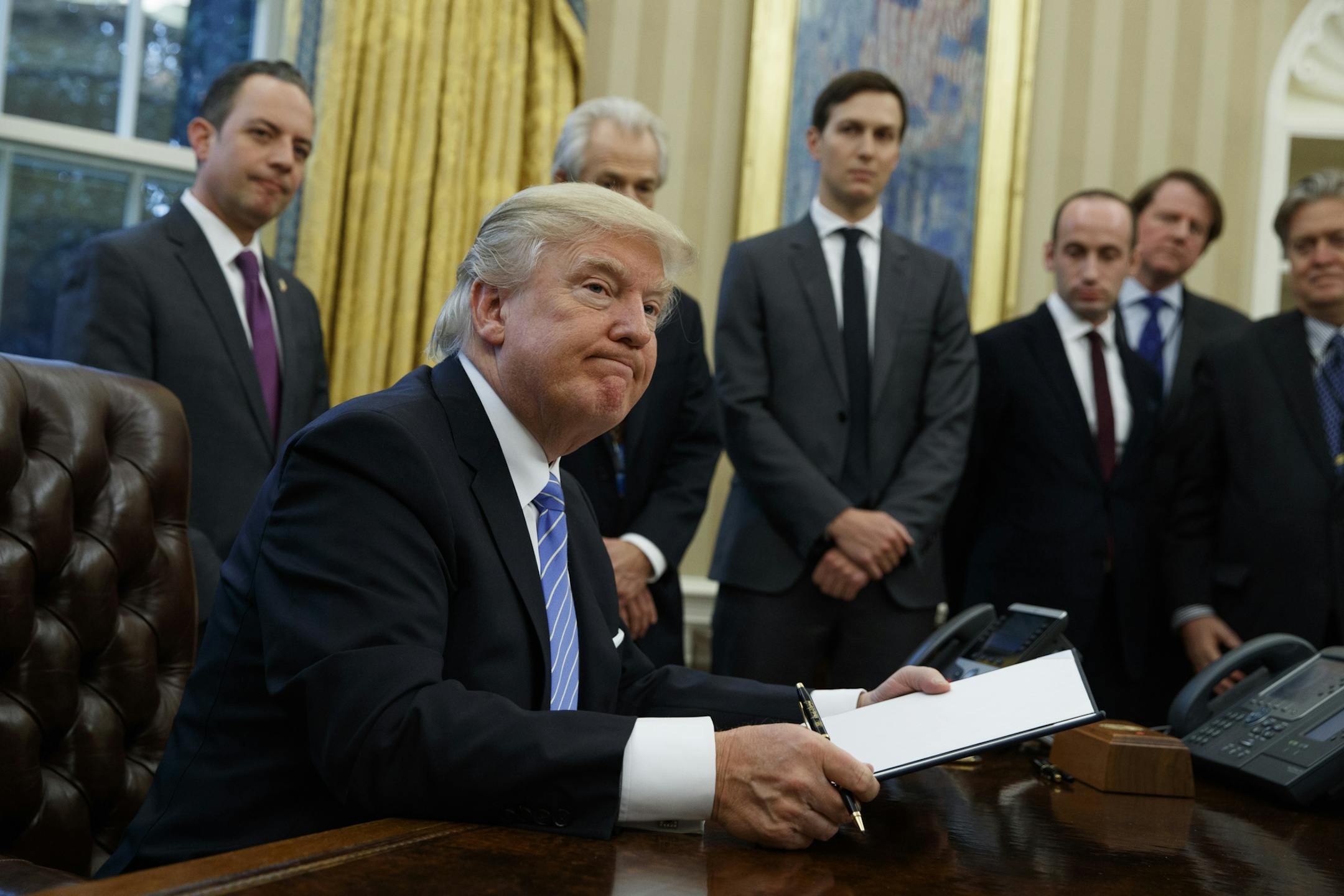 President Donald Trump looks up after signing the final of three executive orders, Monday, Jan. 23, 2017, in the Oval Office of the White House in Washington. (AP Photo/Evan Vucci)
