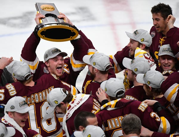 Minnesota-Duluth Bulldogs forward Karson Kuhlman (20) hoisted the NCAA championship trophy over his head while celebrating with teammates following th