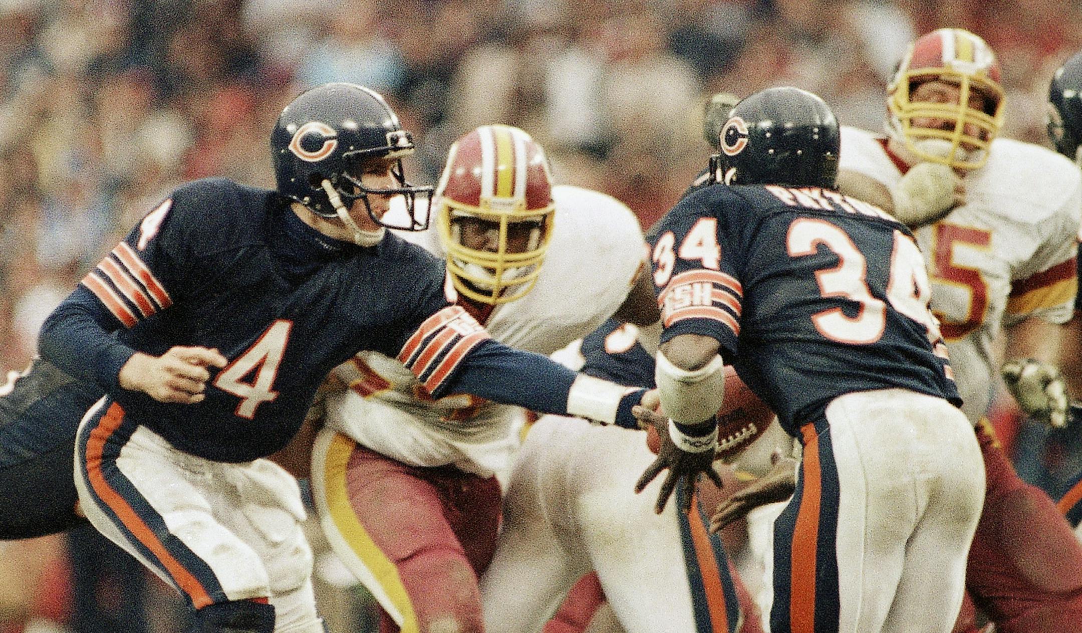 Chicago Bears quarterback Steve Fuller (4), hands off to his running back Walter Payton, 34, during second half action against the Washington Redskins at R.F.K. stadium, Sunday, Dec. 24, 1984 in Washington. The Bears went on to win the game 23 to 19 and will play the San Francisco 49ers for the NFC title on next Sunday, January 6, in San Francisco. (AP Photo) ORG XMIT: APHS164033