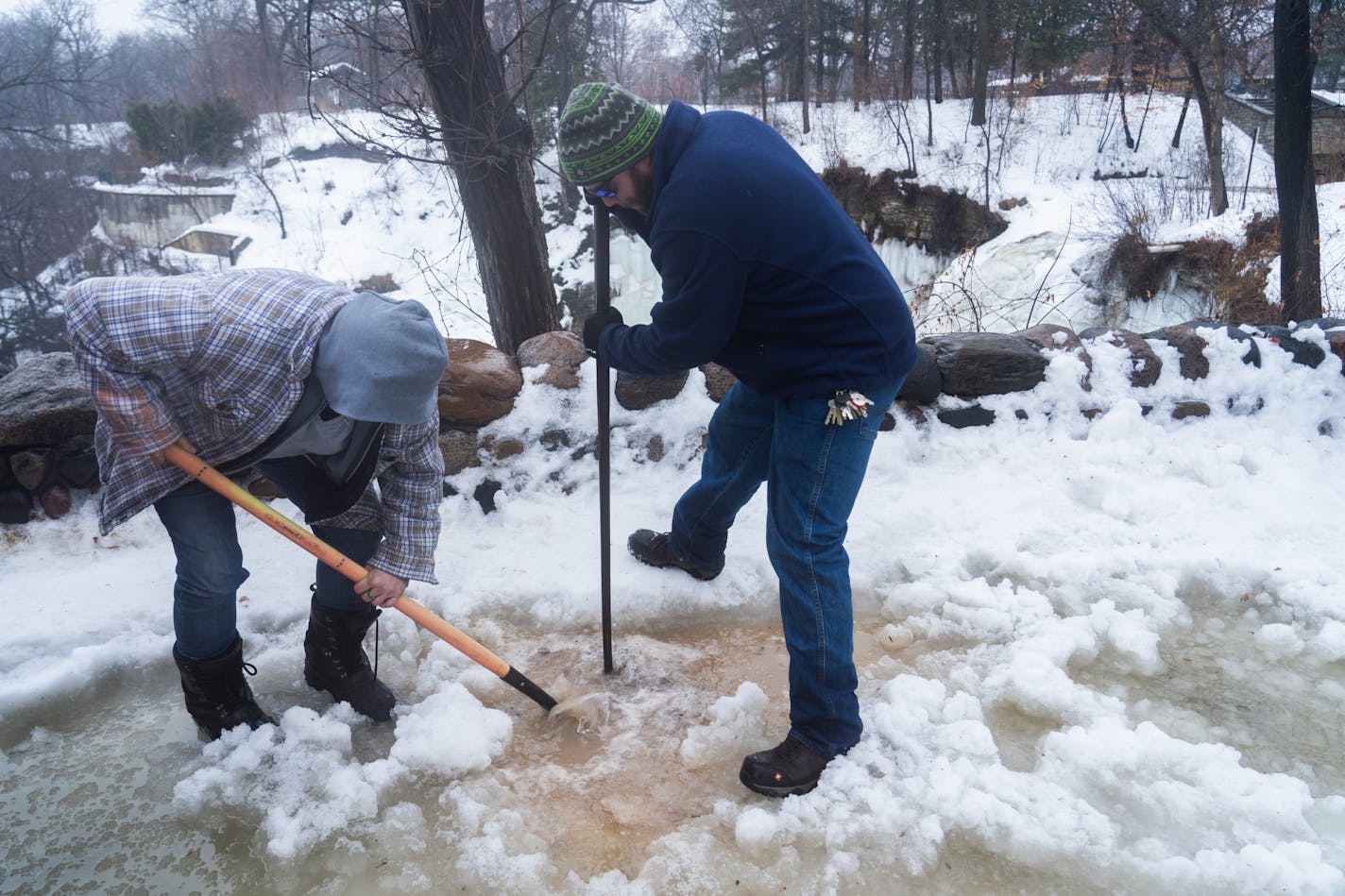 Working from memory and armed with shovels and picks, Minneapolis park keepers Jennifer Dennis and Ryan Susag have been working to clear drains packed with ice and snow at Minnehaha Falls all morning.