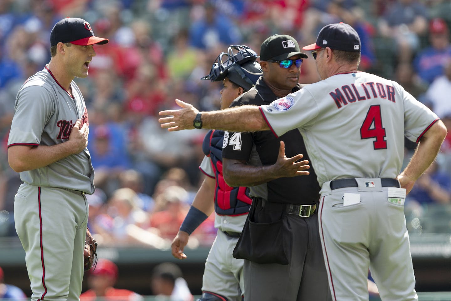 Minnesota Twins relief pitcher Matt Belisle, left, looks on as Minnesota Twins manager Paul Molitor (4) and umpire Alan Porter (64) argue after Belisle was ejected during the sixth inning of a baseball game against the Texas Rangers, Sunday, Sept. 2, 2018, in Arlington, Texas. (AP Photo/Sam Hodde)