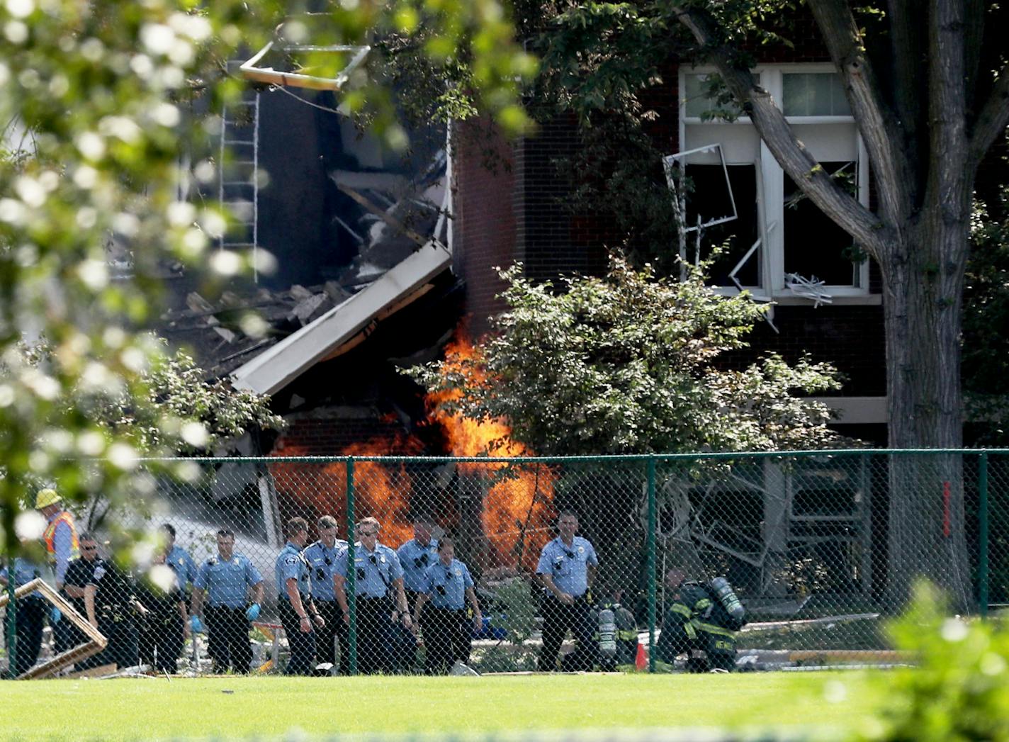 Emergency personnel move away as a gas fire continued to burn after the explosion at Minnehaha Academy on Wednesday, Aug. 2, 2017, in Minneapolis.