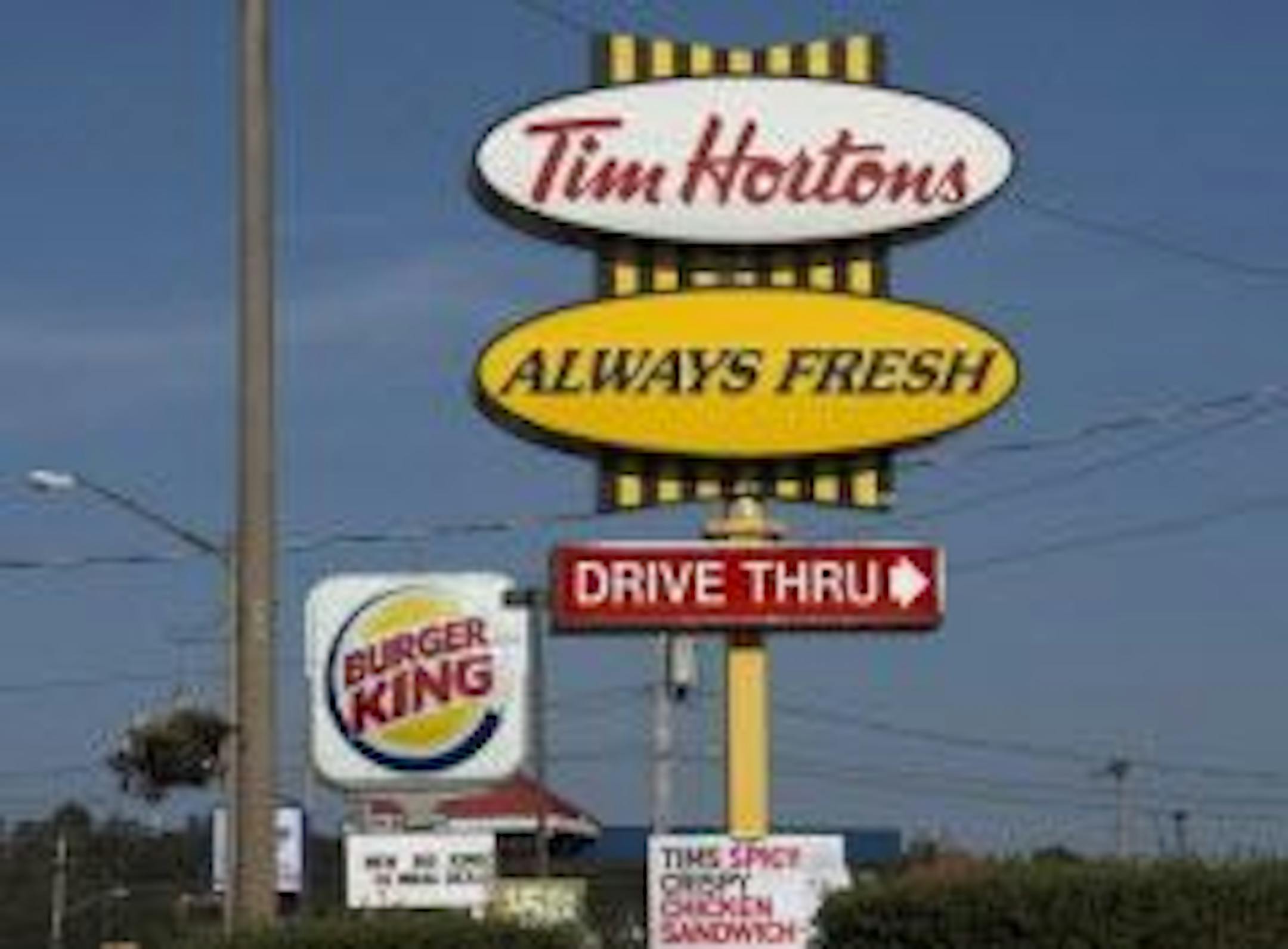 A Burger King sign and a Tim Hortons sign are displayed in Lower Sackville, Nova Scotia, Monday, Aug. 25, 2014.