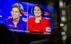 Sens. Elizabeth Warren (D-Mass.) and Amy Klobuchar (D-Minn.) appear on a monitor during a Democratic presidential debate at Drake University in Des Mo